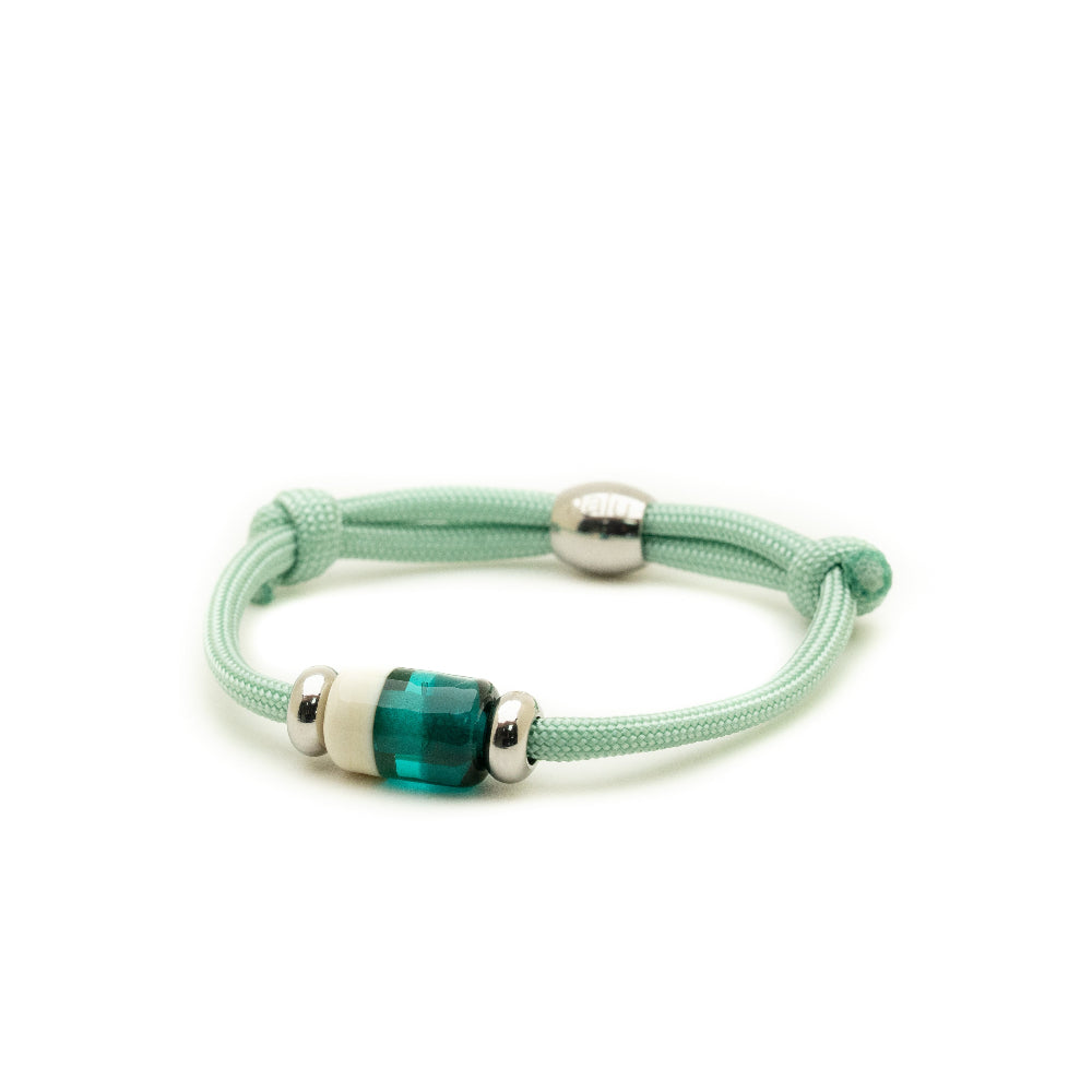 Glass bead on pale green cord bracelet on white background.