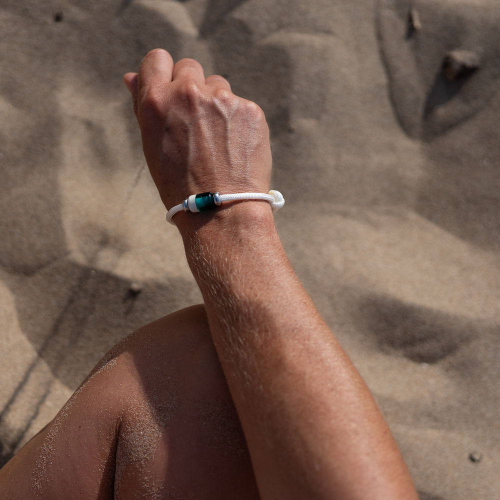 Hand wearing a bracelet while sitting on the beach.
