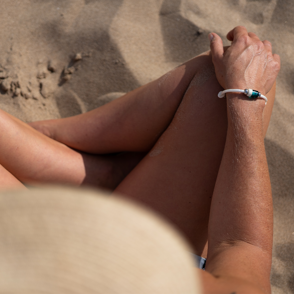 Person wearing a bracelet while sitting on the beach.