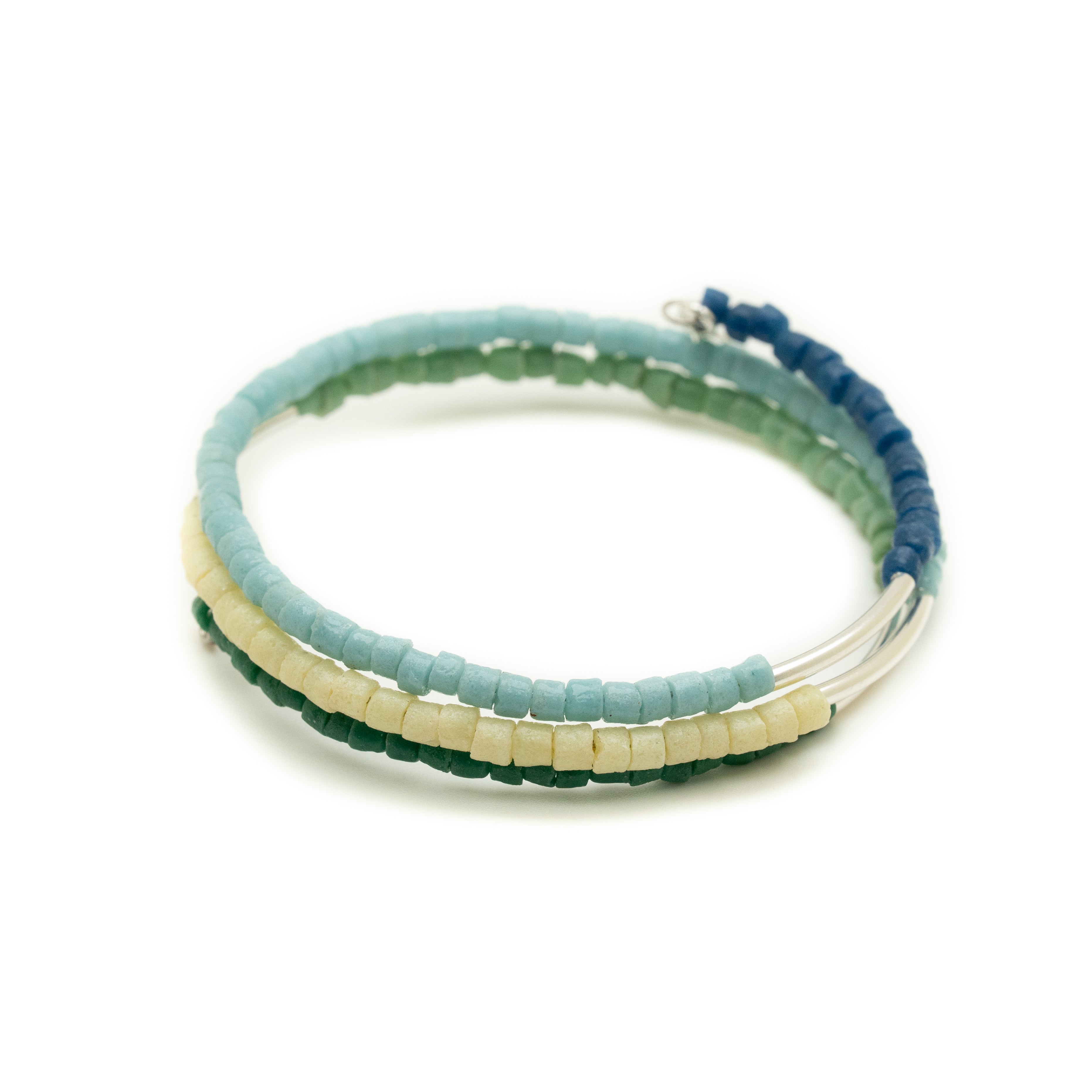 A stack of three multicolored beaded bangles with silver accents, wrapping around a wrist.