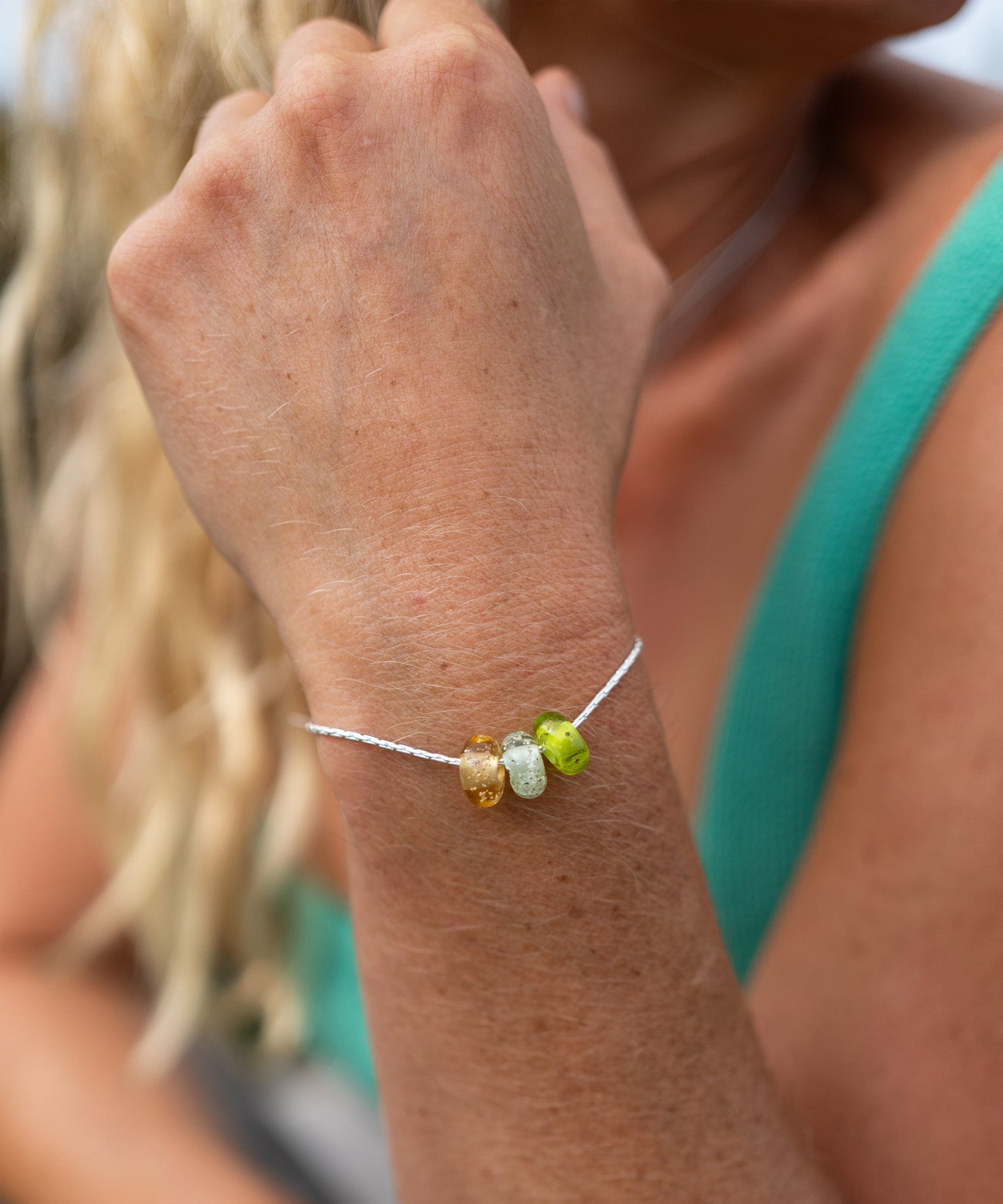 Close-up of a wrist wearing a bracelet with colorful beads, blurred background