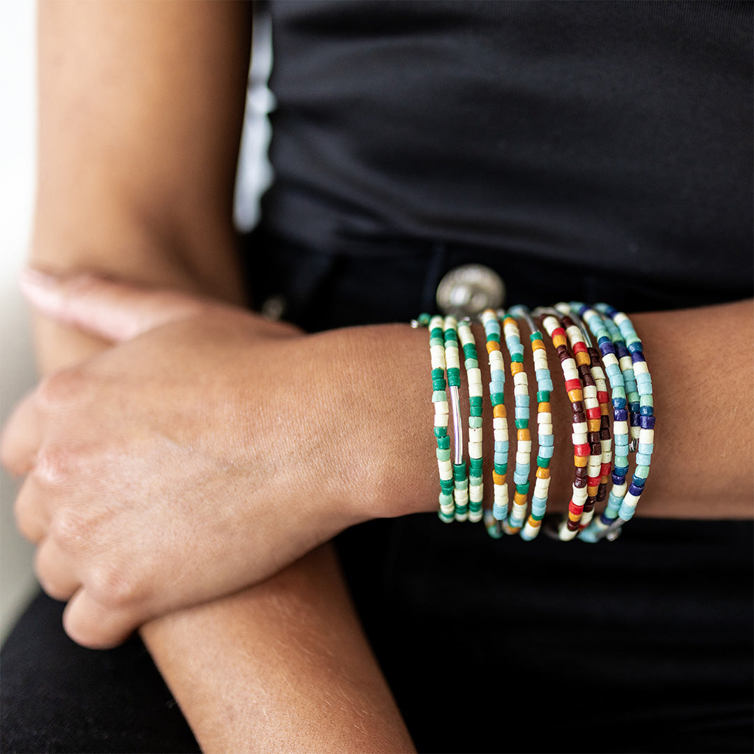 Close-up of arms wearing colorful beaded bracelets.