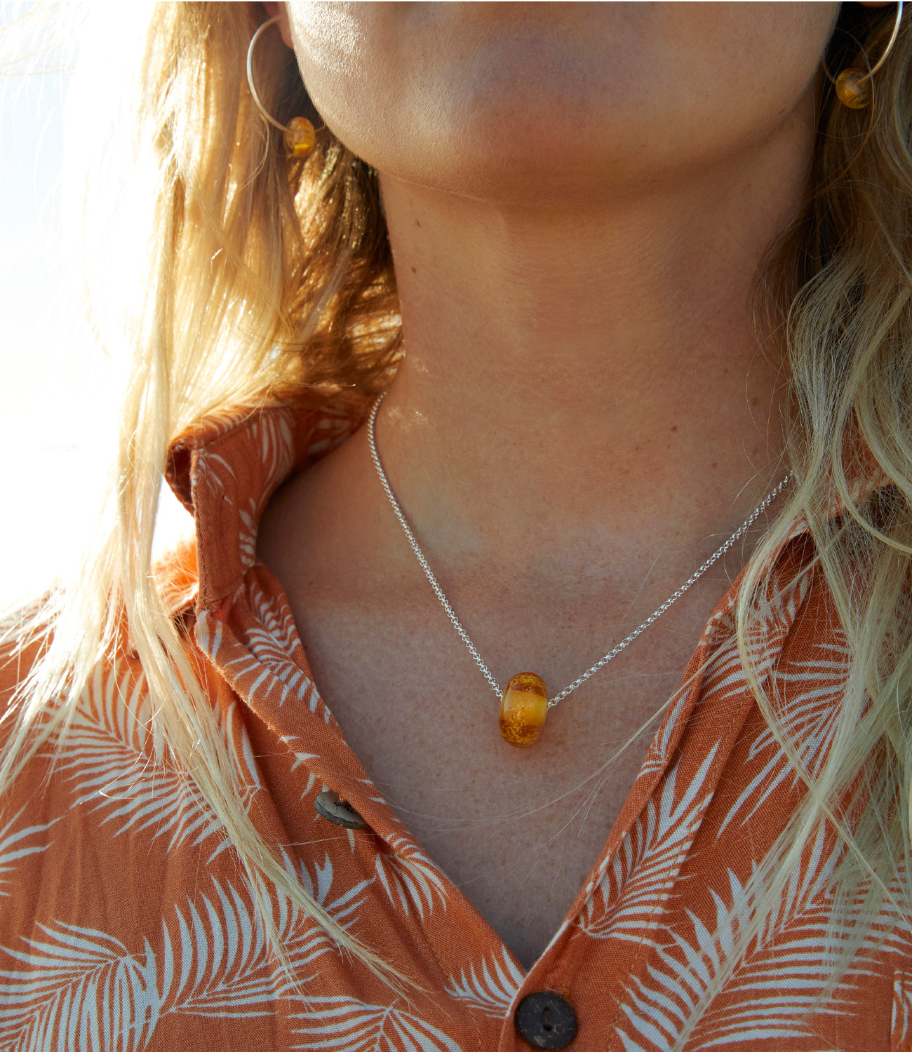Girl on beach wearing amber glass sand bead necklace and earrings.