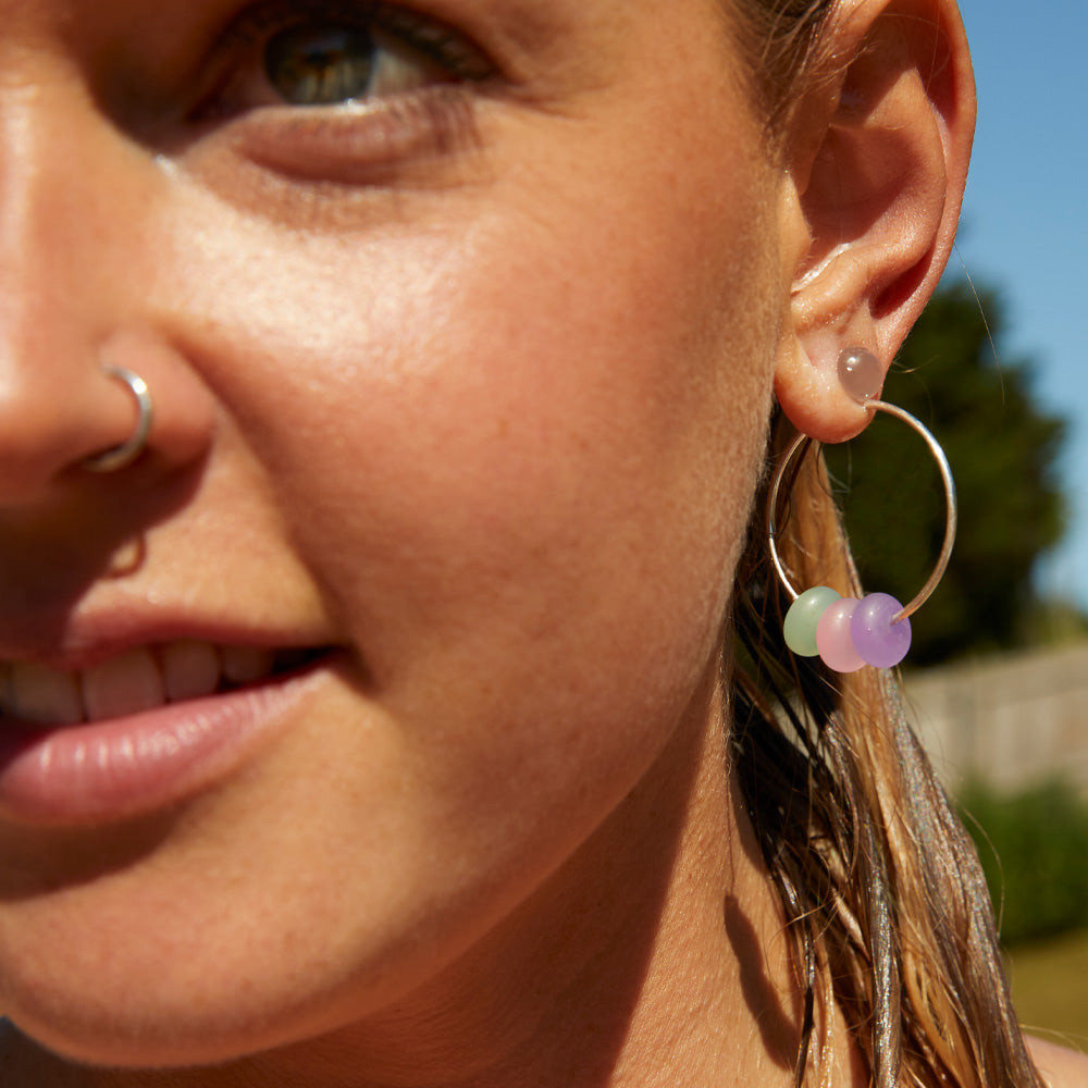 Girl wearing colorful beaded earring silver hoops.
