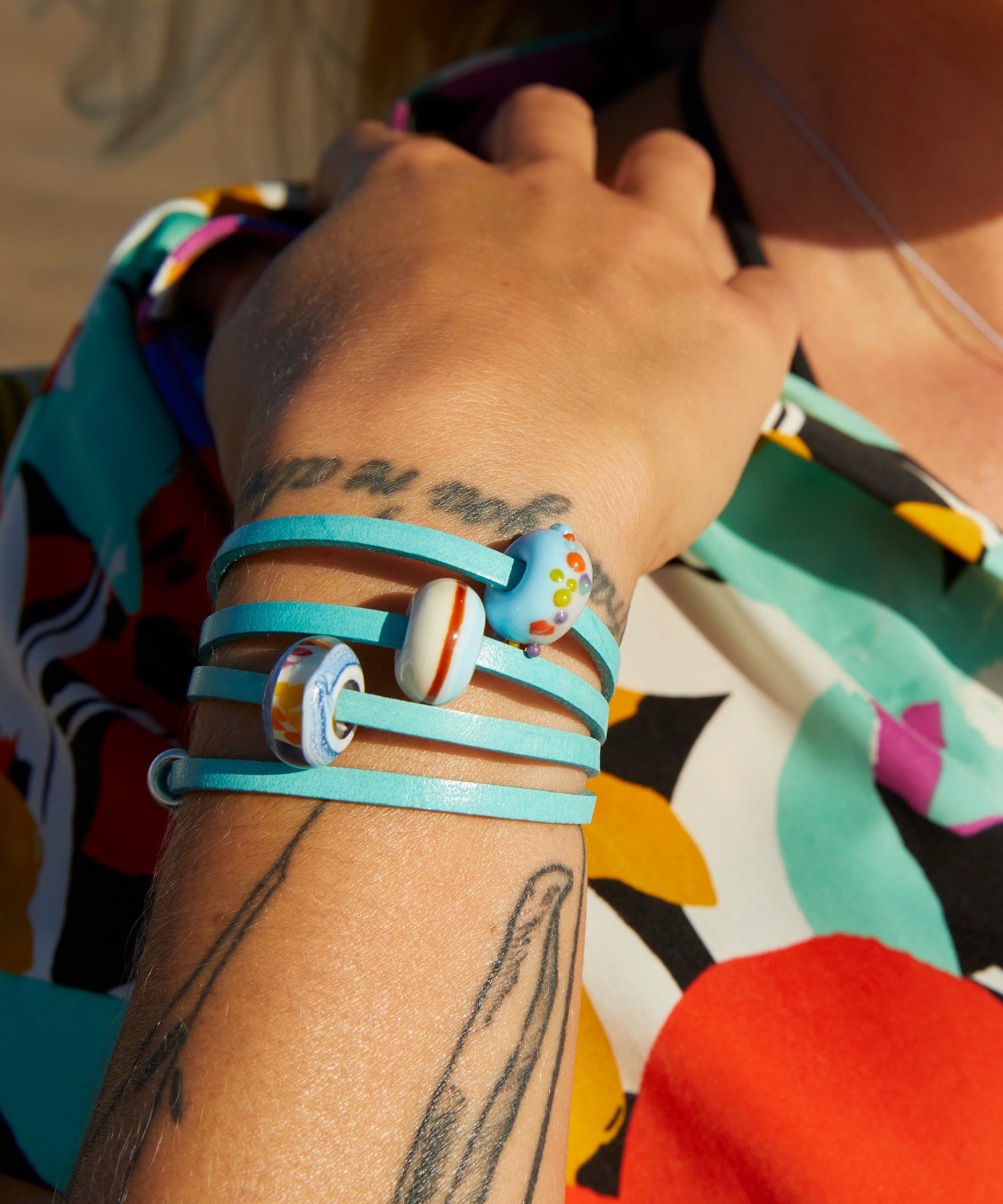 Colourful glass beads worn on turquoise leather wrap bracelet.