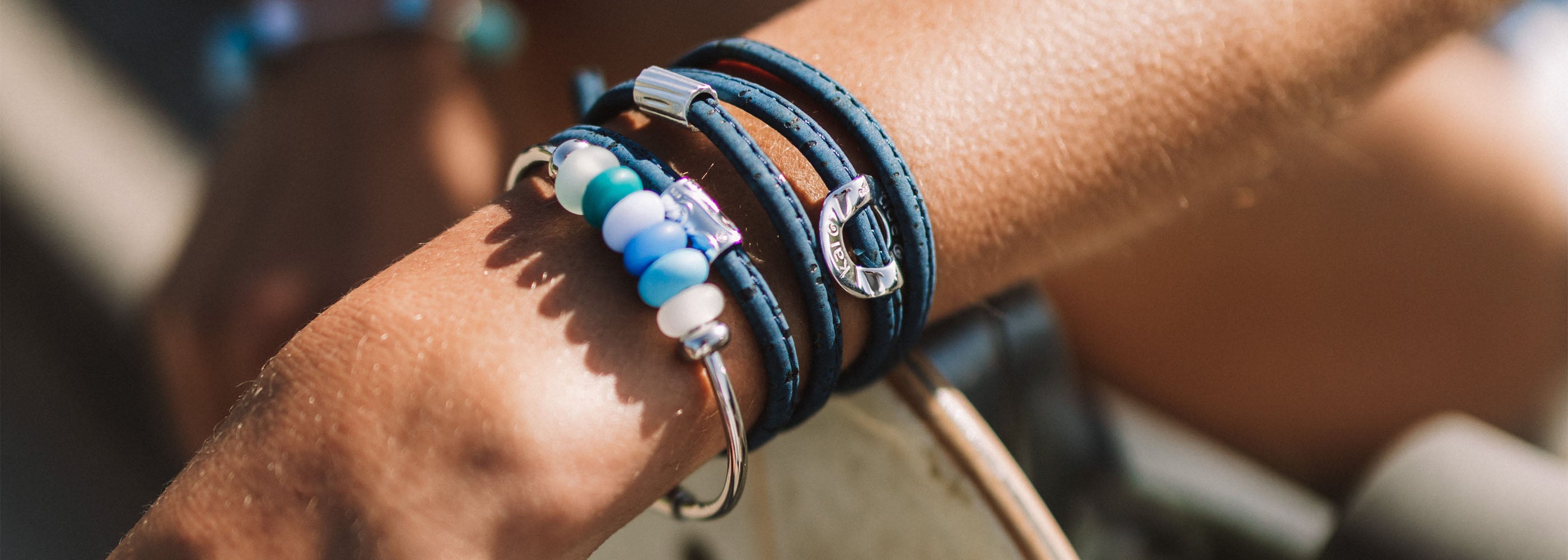 Blue glass bead bangle and navy cork bracelet worn by person with skate board.