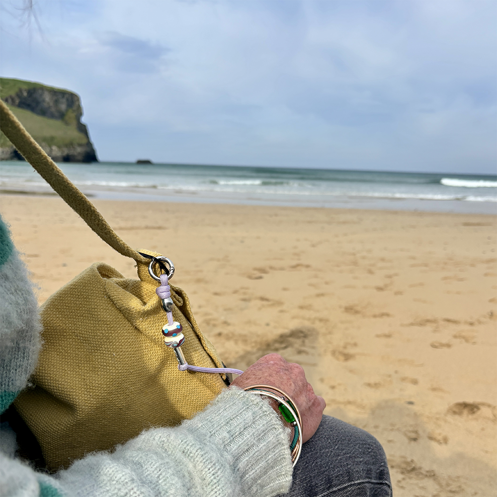 Person holding a yellow bag on a beach with ocean and cliffs in the background