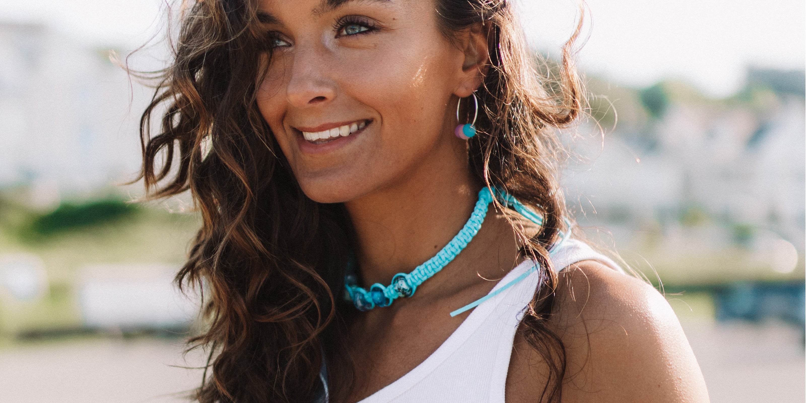 Turquoise vegan cord macrame style necklace with glass beads and colourful silver hoops worn by surfer girl.