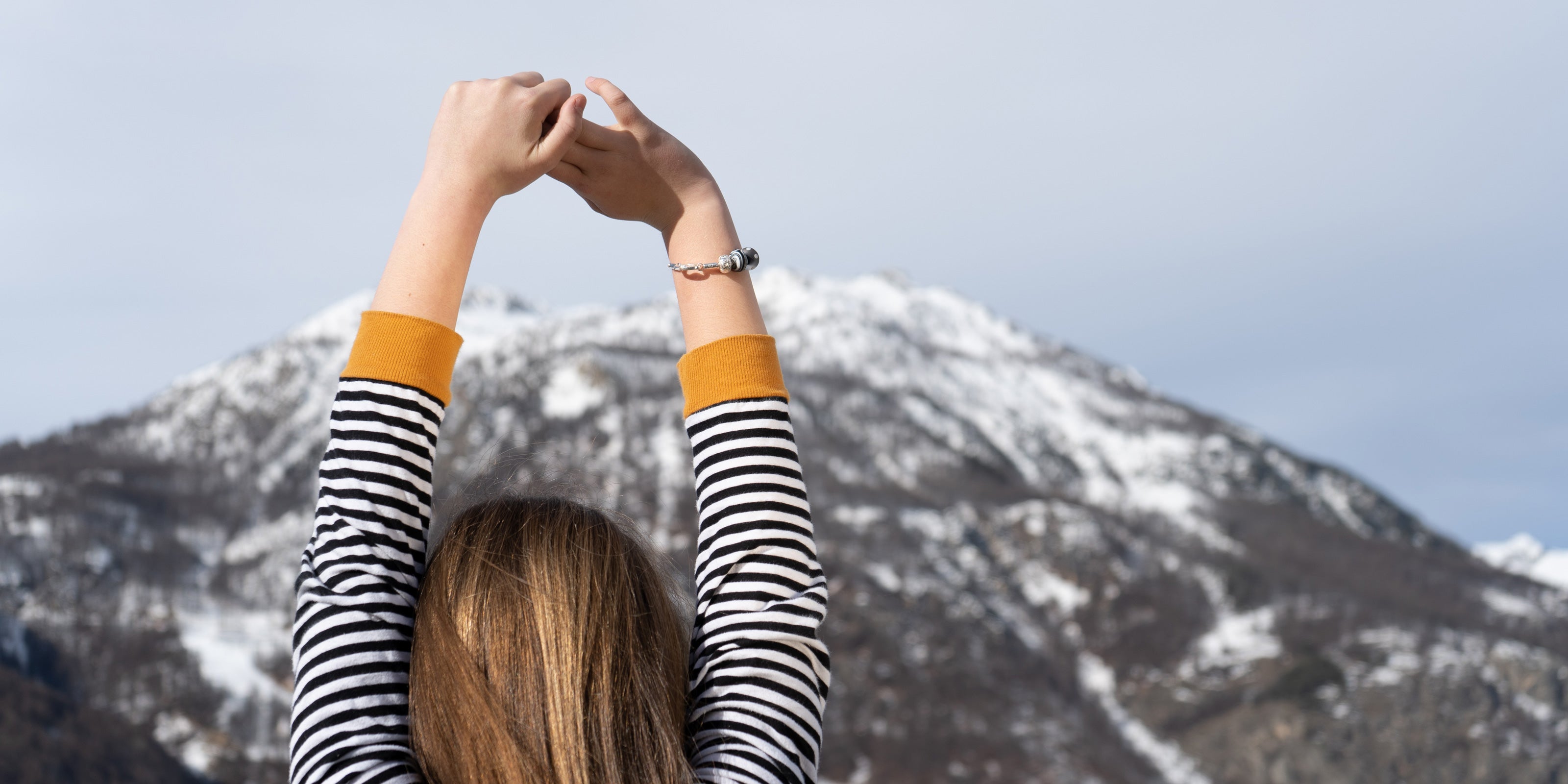Glass beads inspired by French mountain resorts worn by girl next to snowy mountains in France.