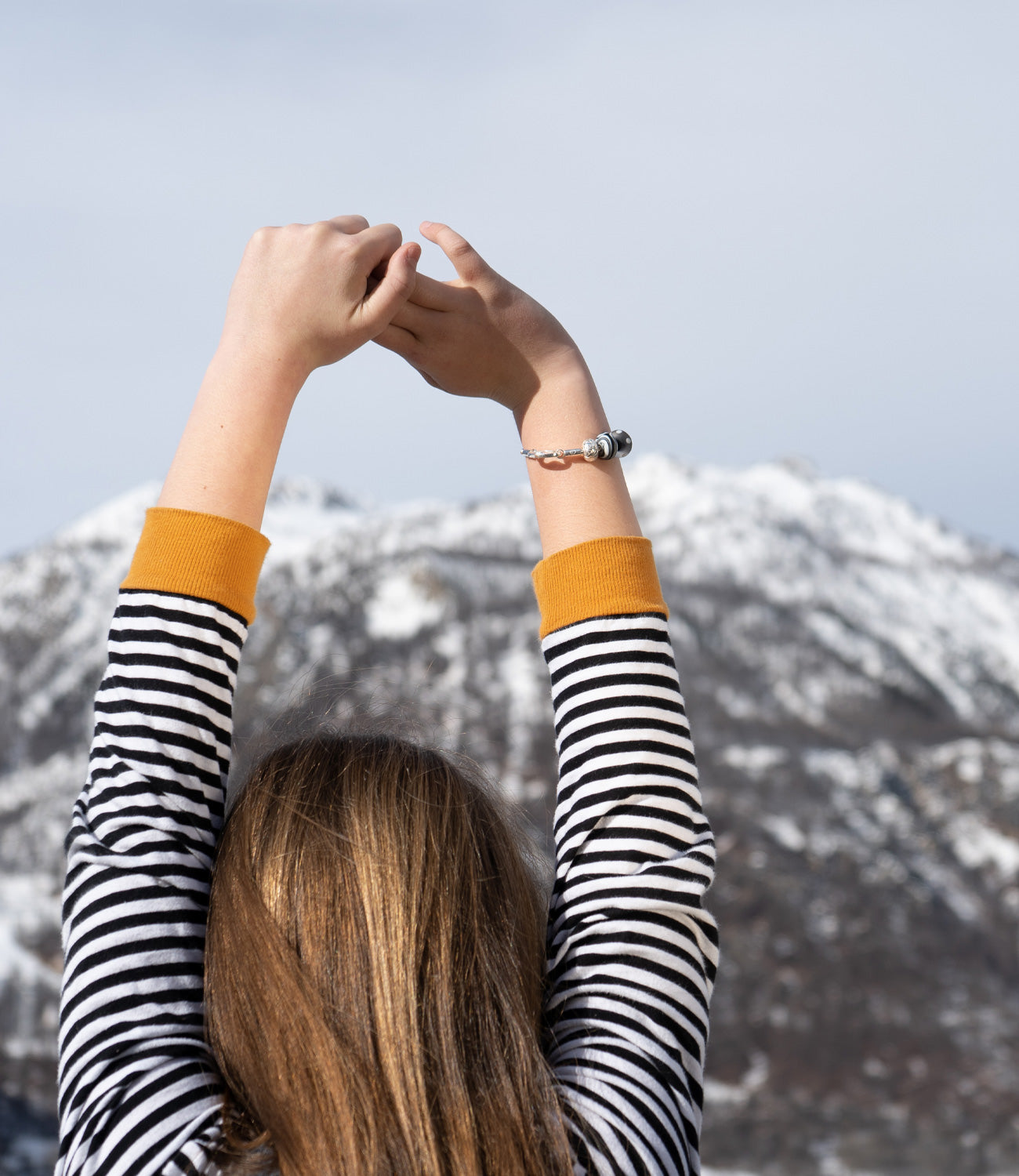 Glass beads inspired by French mountain resorts worn by girl next to snowy mountains in France.