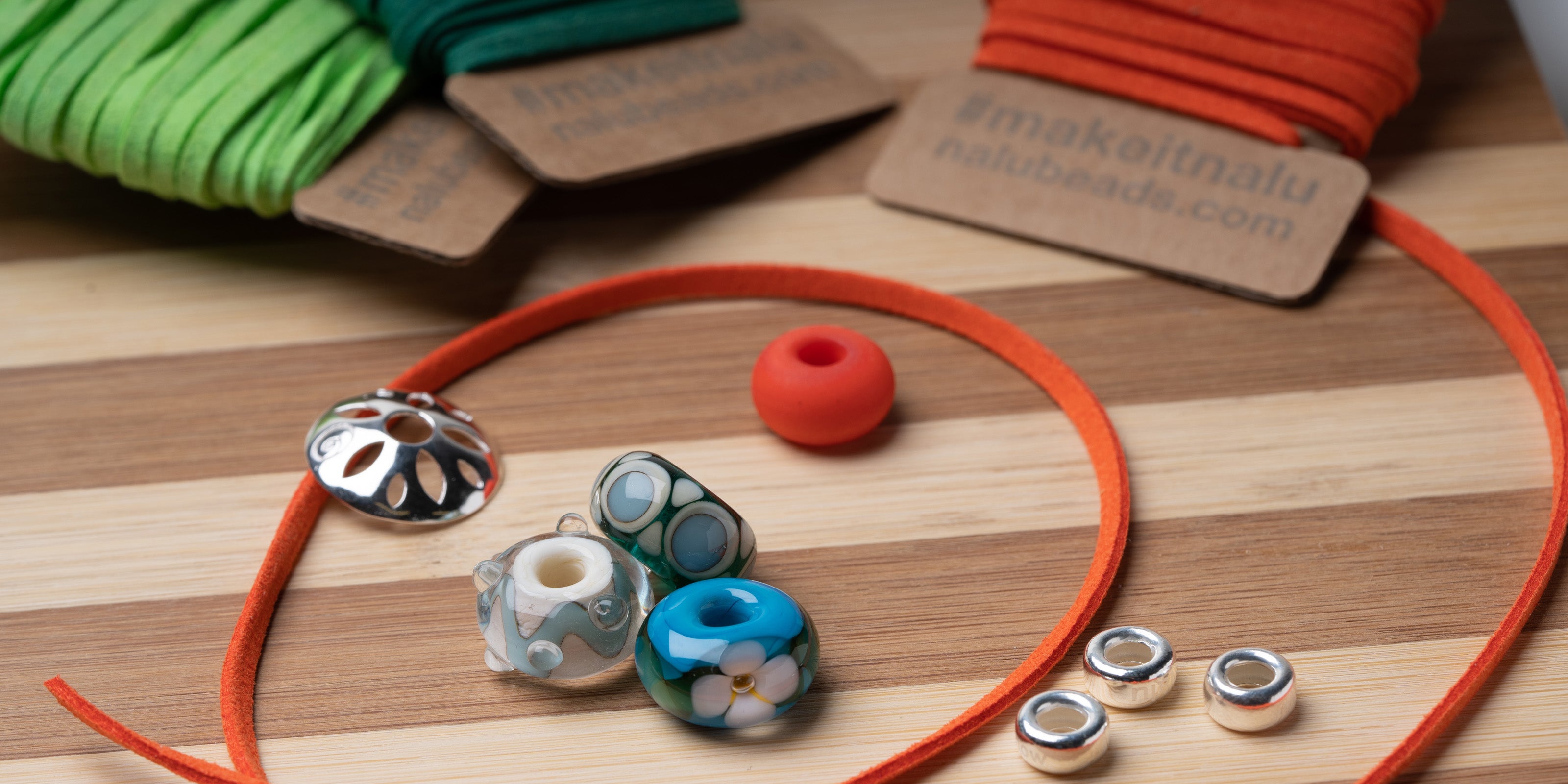 Beaded necklace with colorful beads and orange cord on a wooden surface with brand name visible.