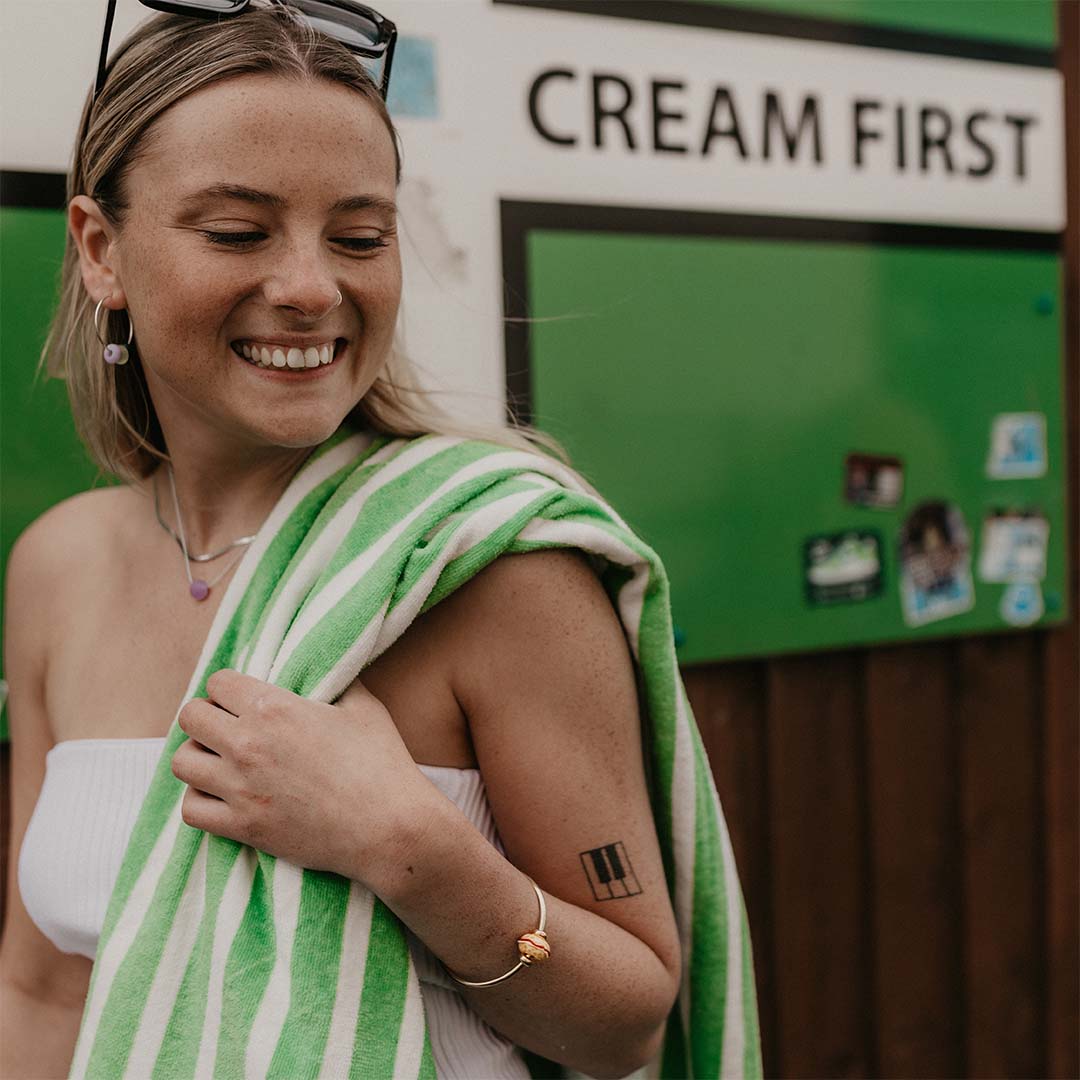 Woman wearing a bangle with a Devon cream tea bead in for of Devon cream first sign.