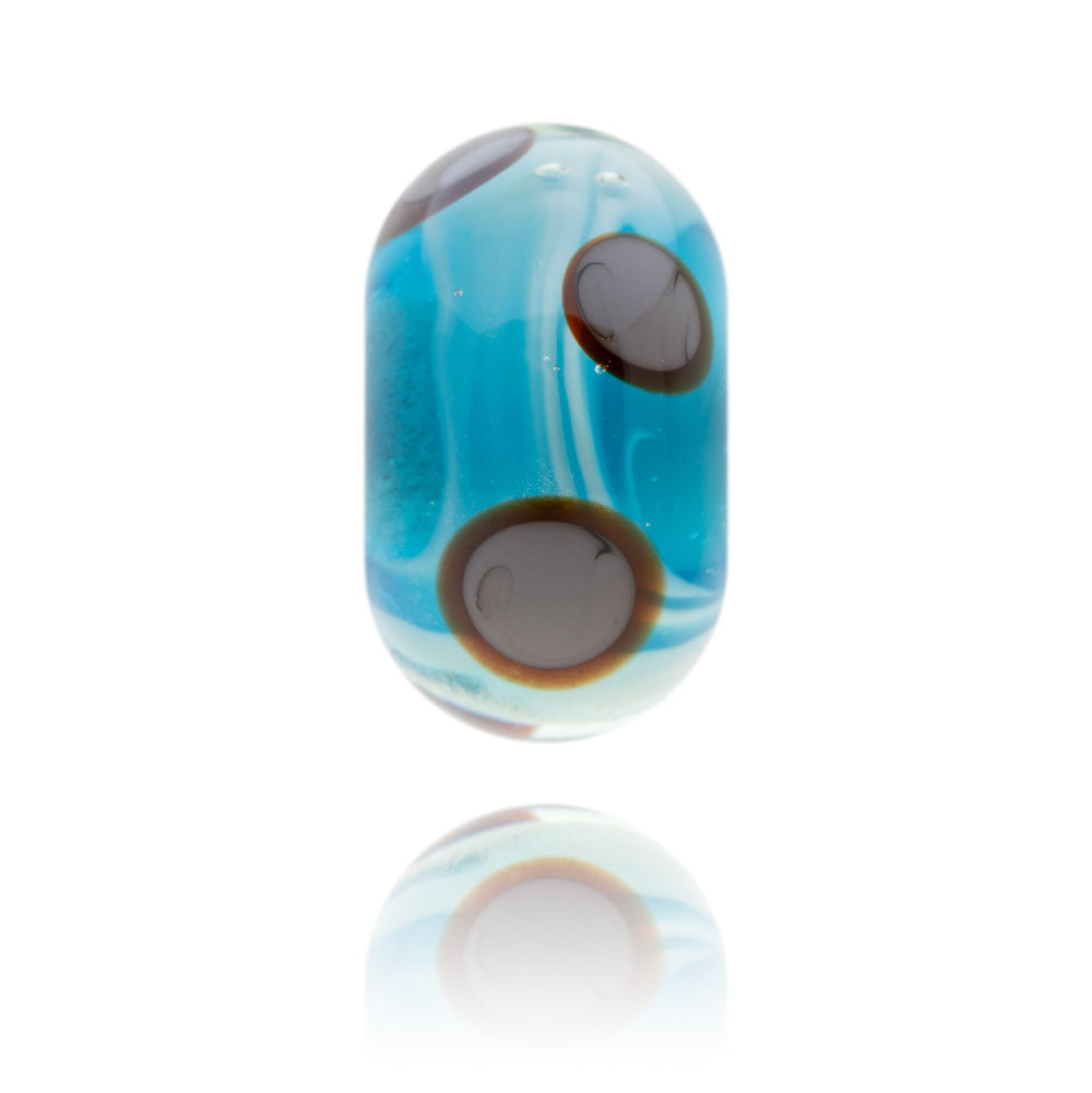 Turquoise glass bead with brown circular patterns on the surface representing Findhorn in Scotland.