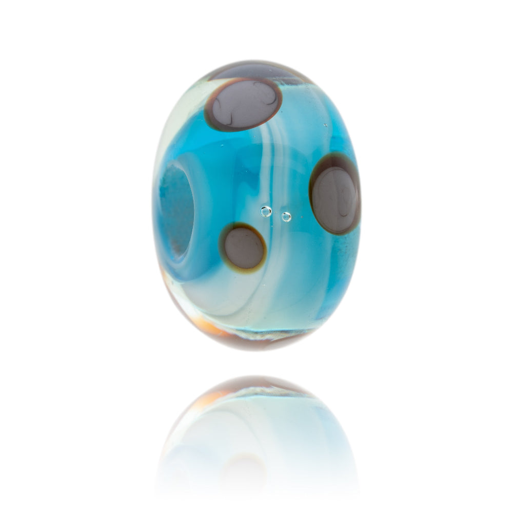 Turquoise glass bead with brown circular patterns on the surface representing Findhorn in Scotland.