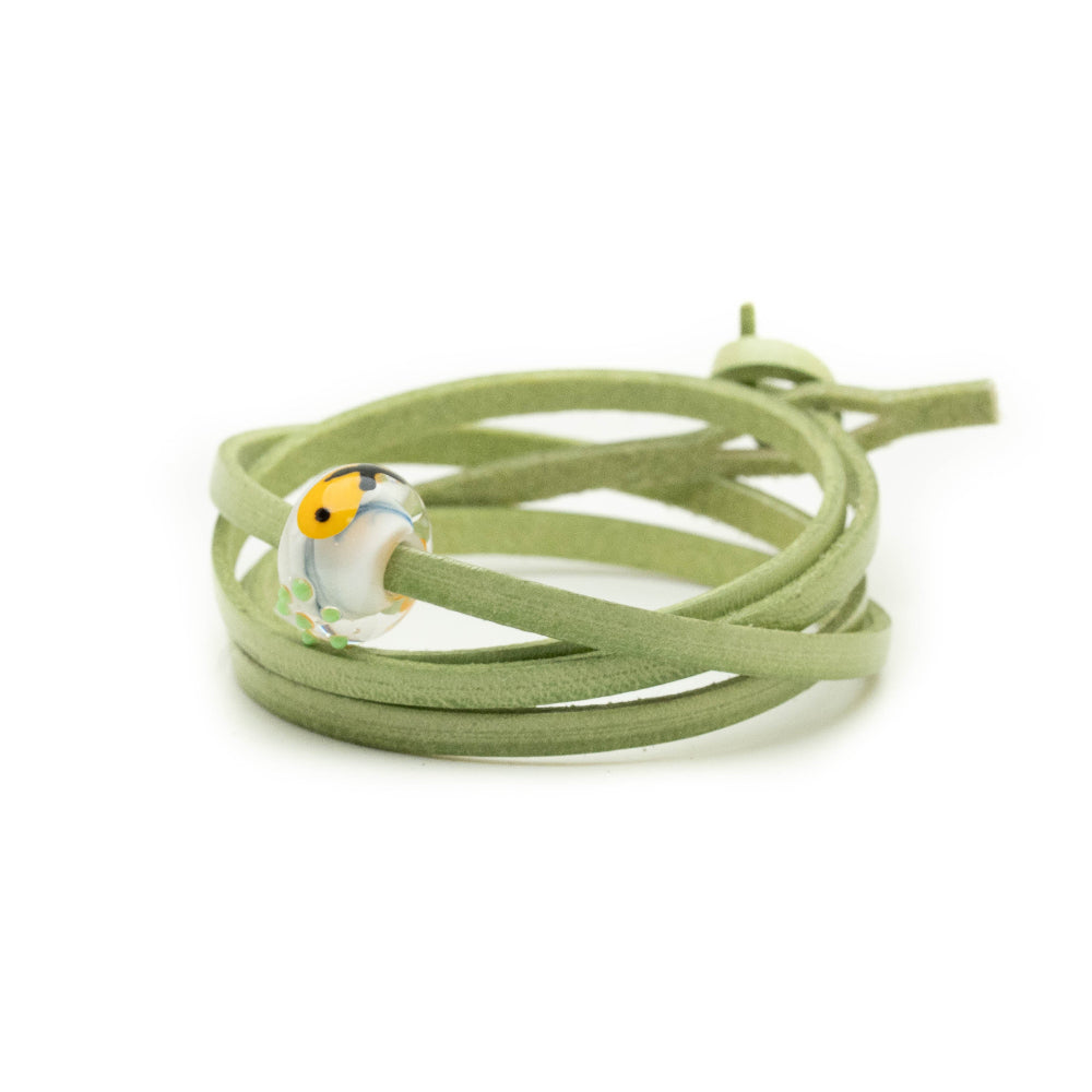 Green leather wrap bracelet with patterned fish and chips glass bead attached.