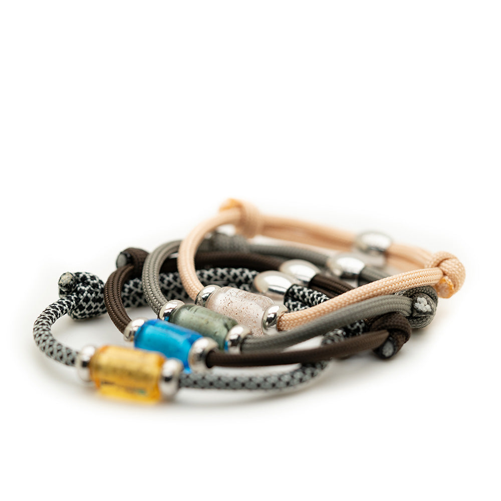 Paracord bracelets in various colours with barrel shaped glass beads attached.