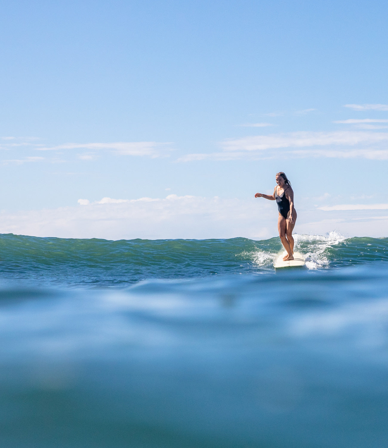 irl surfing on her longboard surfboard in the sea in Australia.