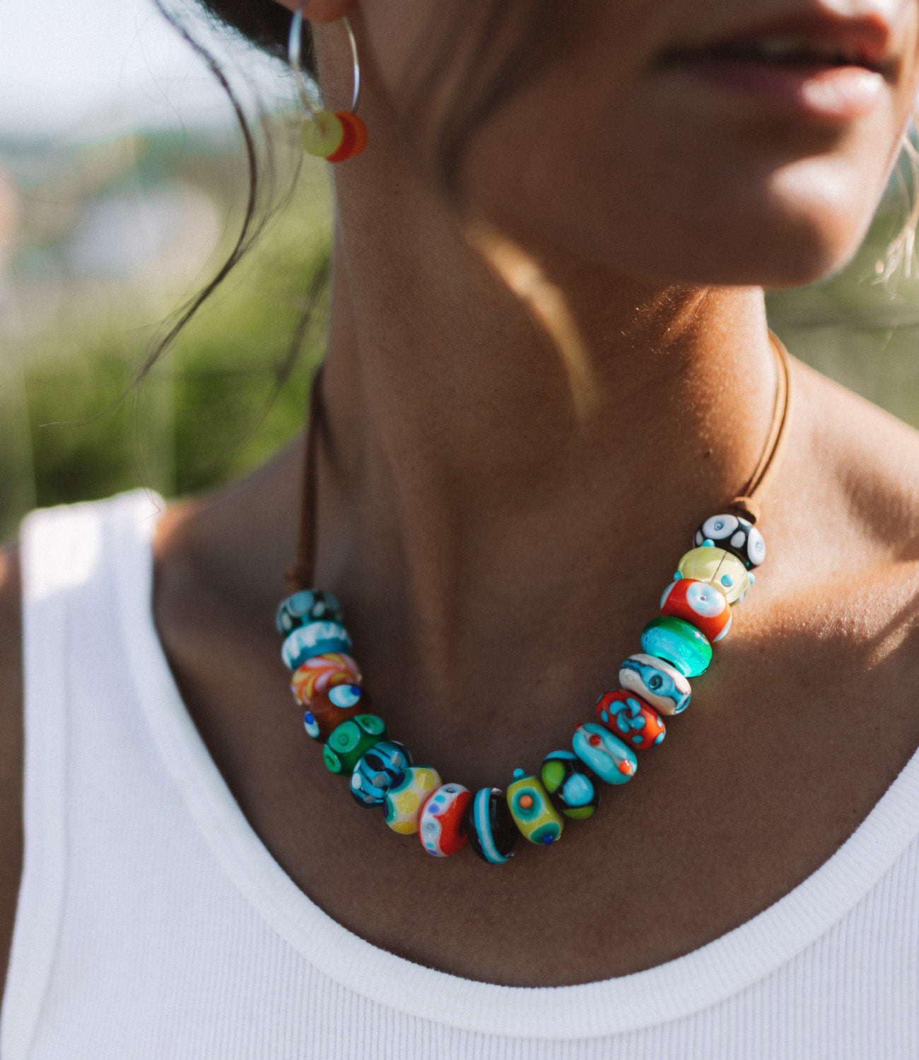 Multicolour glass beads strung on cord necklace worn by skater girl at the beach.