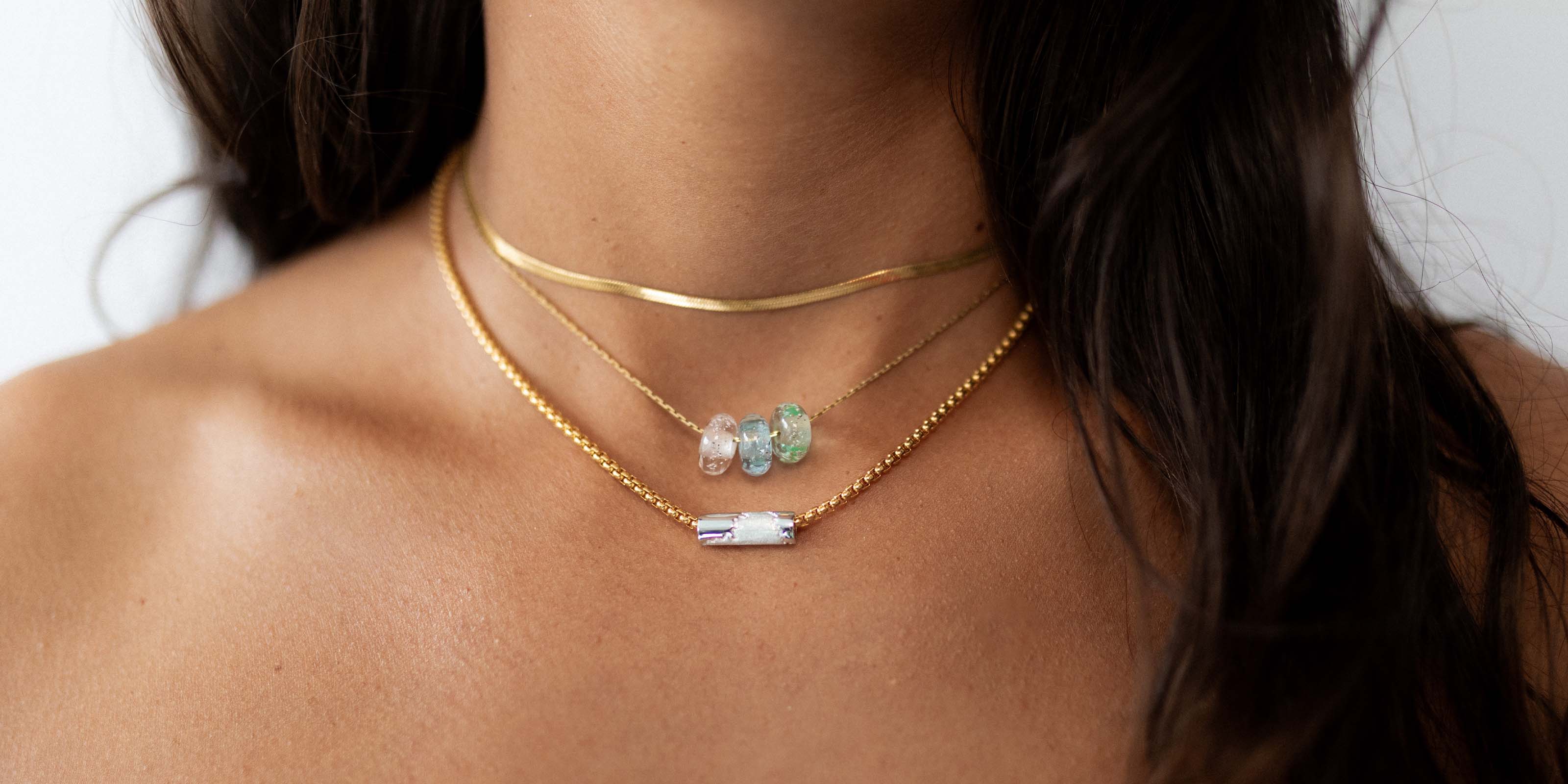 Gold layered necklaces with glass beads and silver charms.