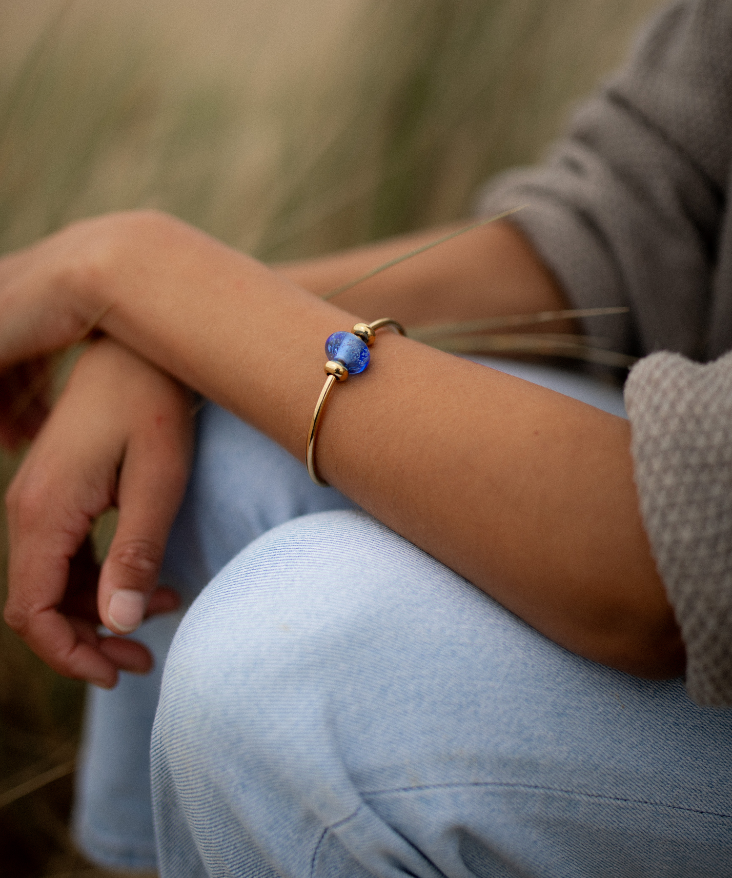 Dark blue beach sand bead worn on gold bangle.