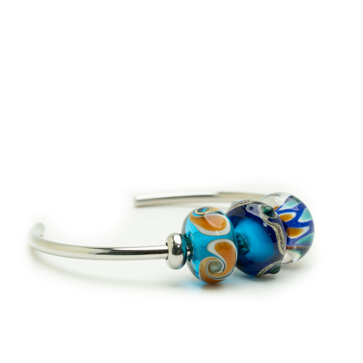 A silver-toned metal bangle bracelet featuring two decorative glass lampwork beads, one in vibrant blue with white swirls and the other in blue, orange, and white swirls, set against a plain white background.