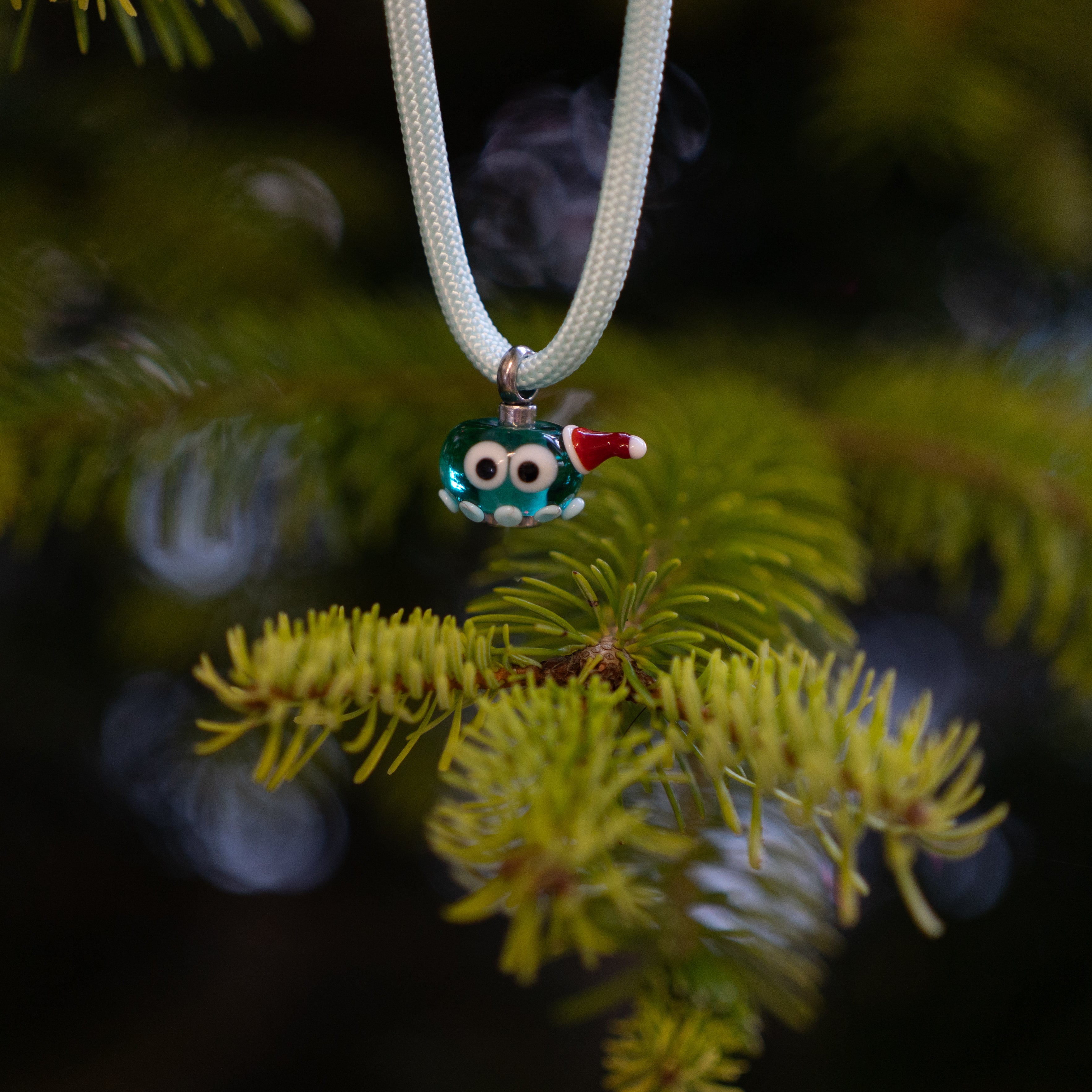 Christmas-themed pendant on a string hanging from a tree branch