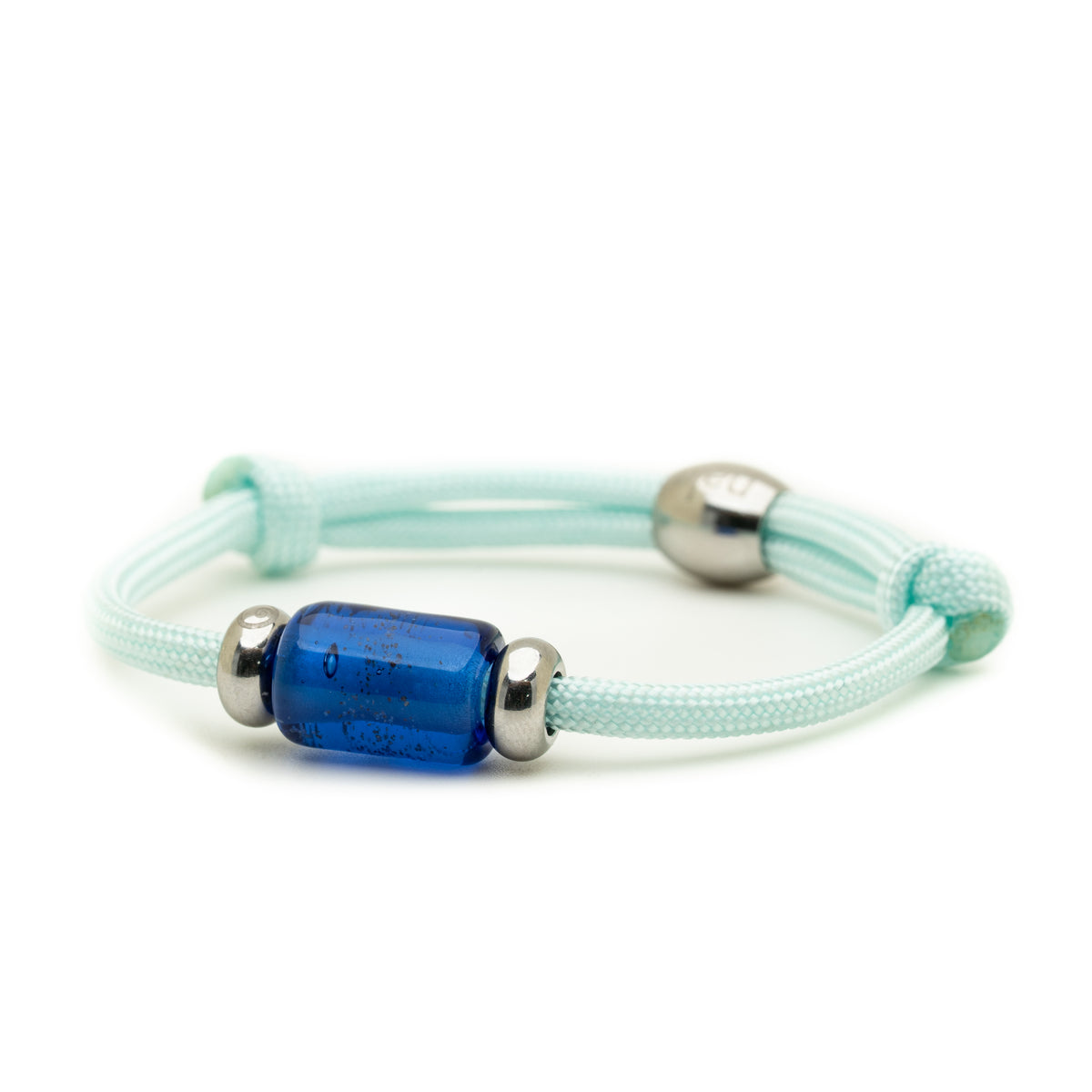 A light mint green braided cord bracelet featuring a central textured blue glass bead flanked by two polished silver metal spacers, shown on a clean white background.