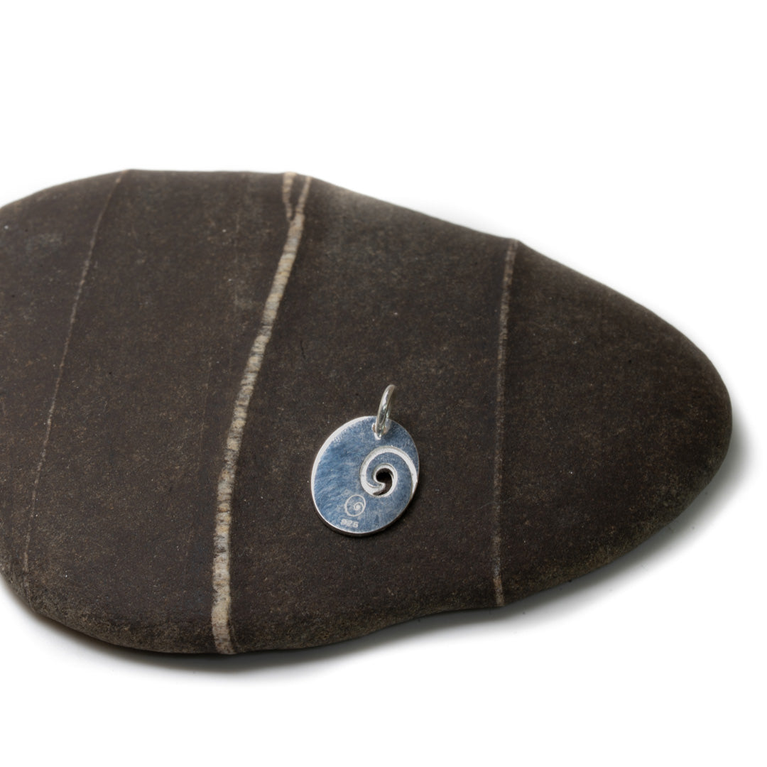 Silver spiral pendant on a striped stone