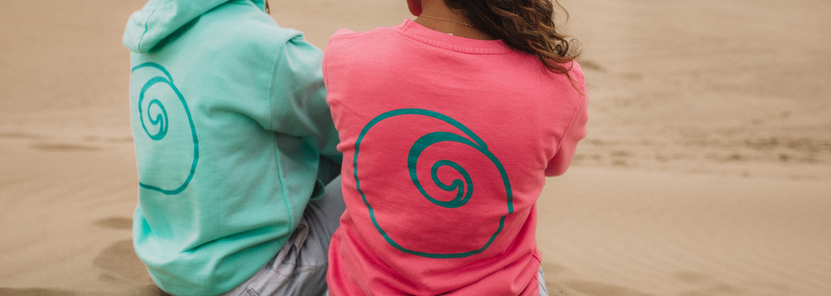 Pink and Mint Nalu Sweatshirts worn by girls on beach.