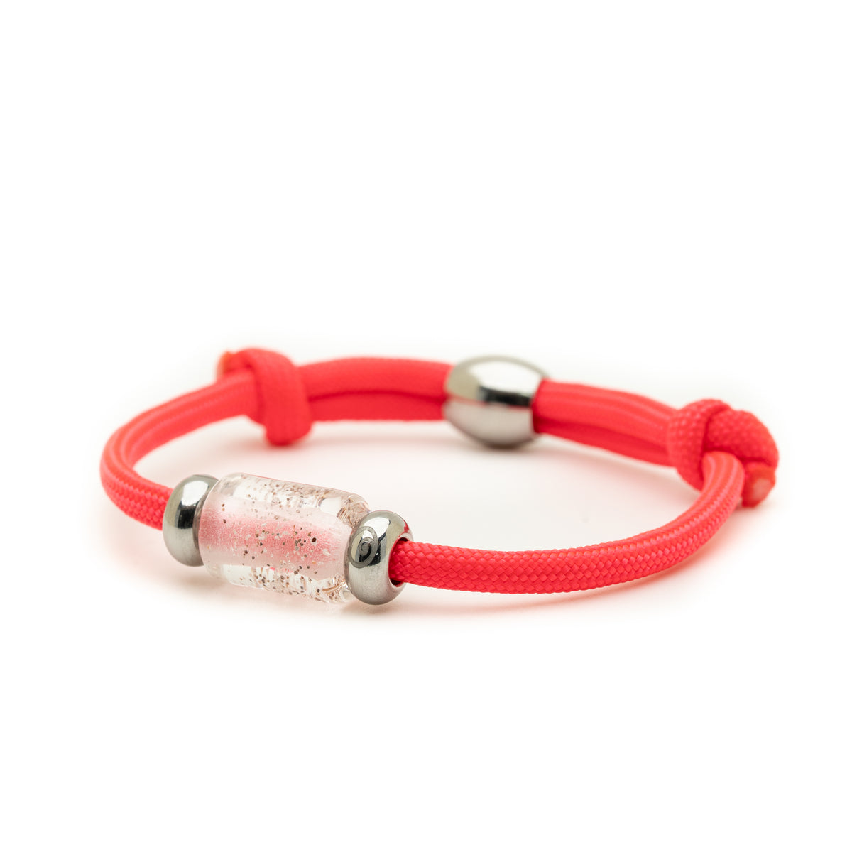 A neon pink braided cord bracelet with a clear cylindrical bead filled with pink glitter, flanked by two silver metal spacers, on a white background.