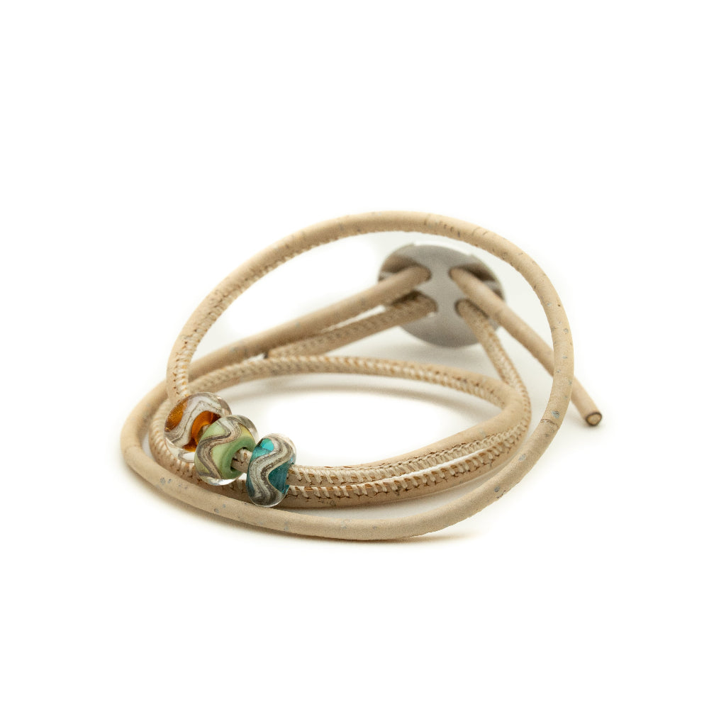 Beige cord bracelet with metal and bead accents on a white background