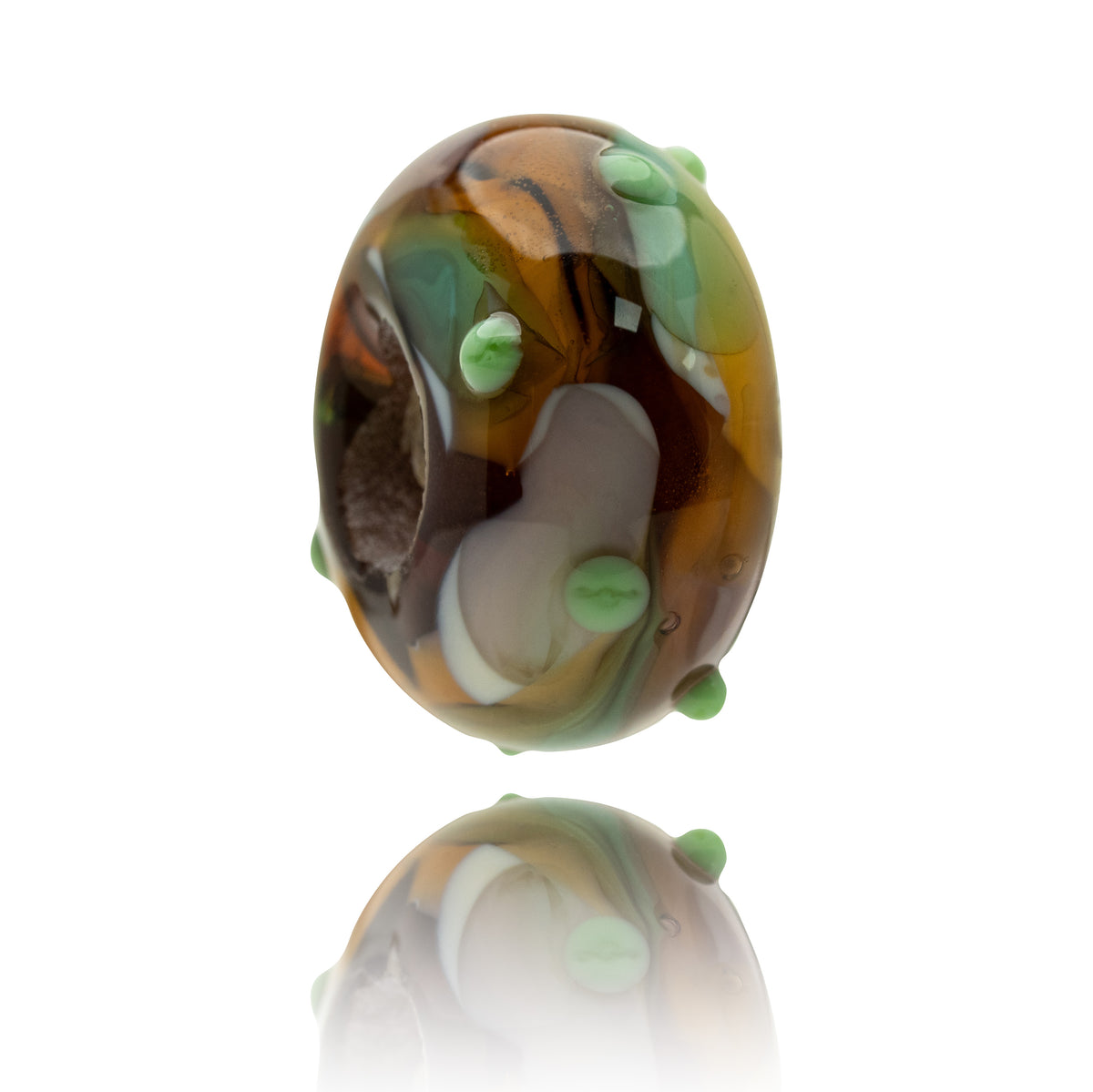 A single oval glass lampwork bead with a marbled pattern of brown, amber, white, and green, featuring raised light green bubble details, shown on a reflective white surface.