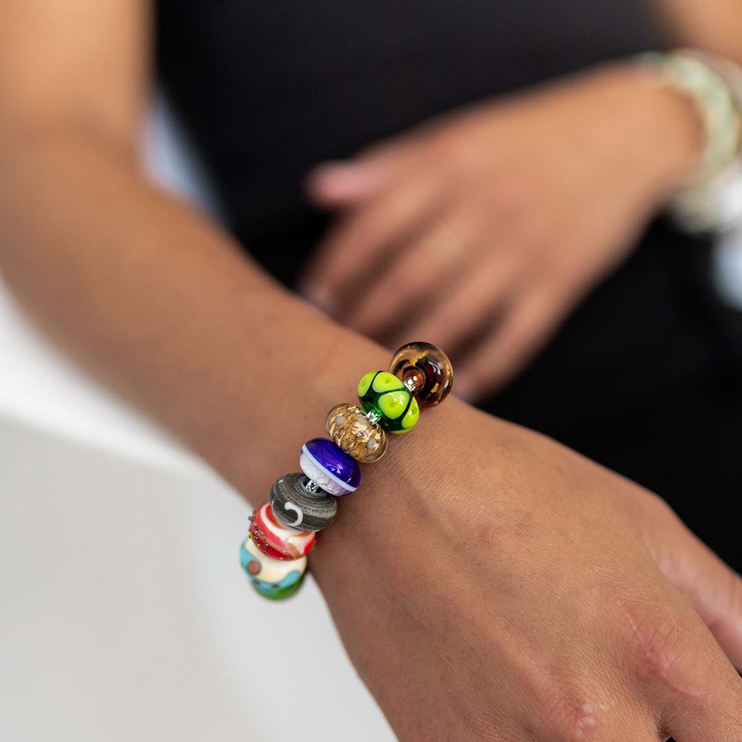 Woman wearing a black vest wearing a sterling silver bracelet with blue, green patterned glass beads.