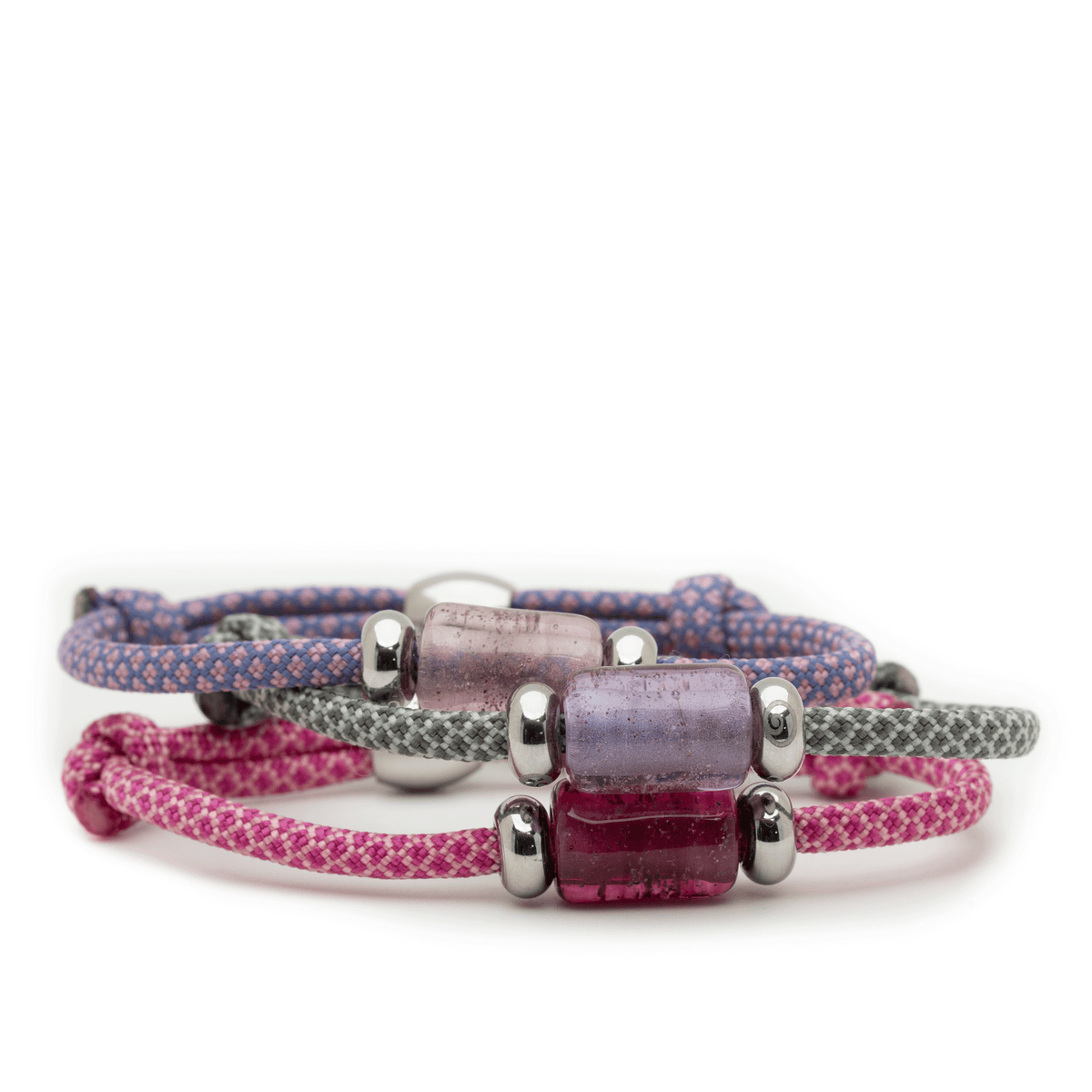 Three woven cord bracelets with silver-toned cylindrical beads and a translucent rectangular bead, shown in pink, purple, and gray on a white background.