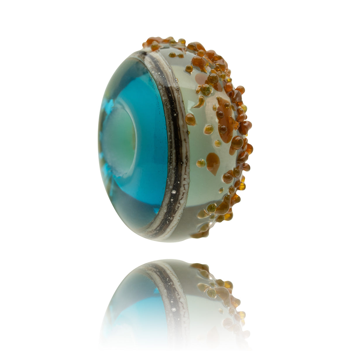 A single round glass lampwork bead with a vibrant blue center, a textured beige rim, and orange-brown bubble details, shown on a white background with a soft reflection below.