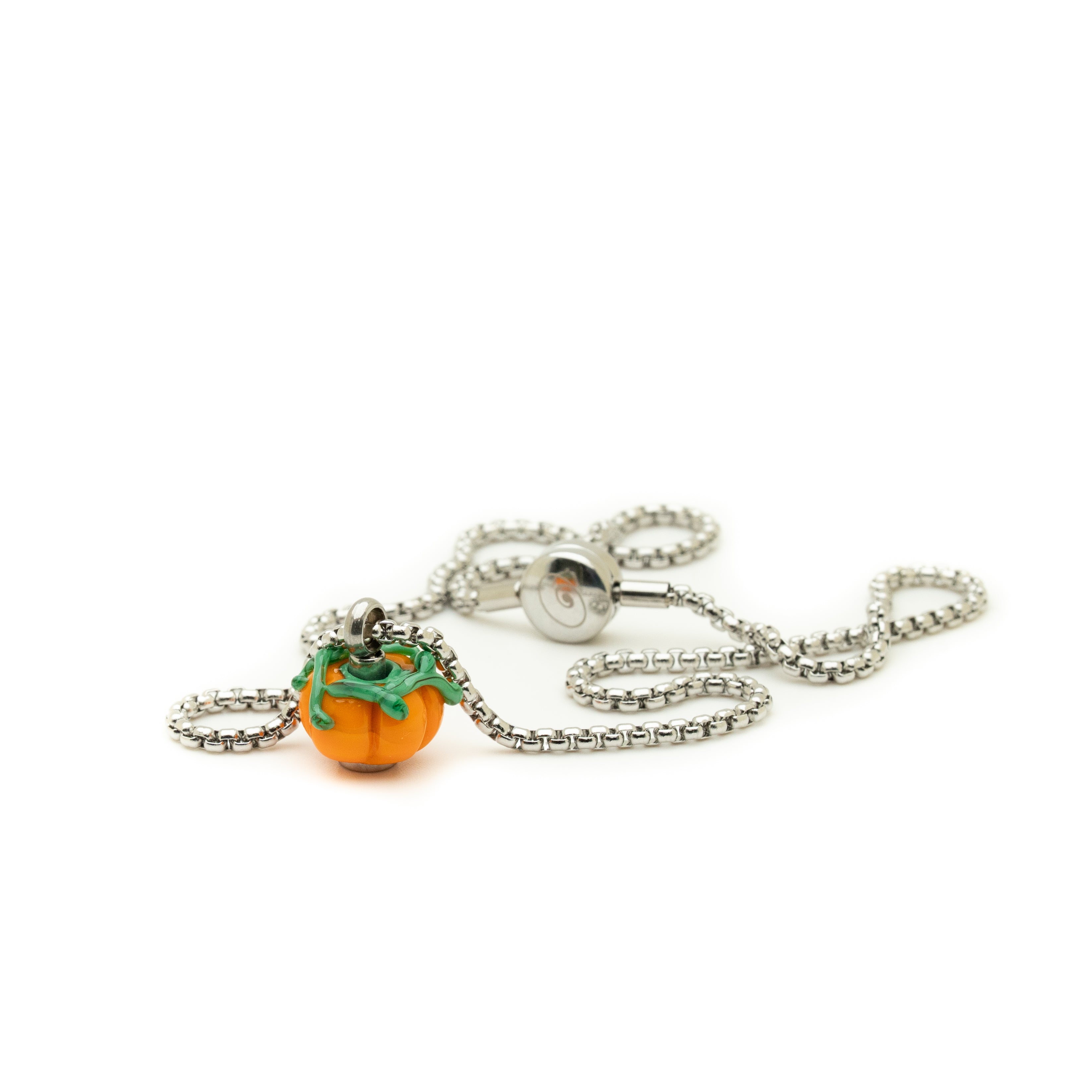 Pumpkin-shaped pendant on a chain against a white background
