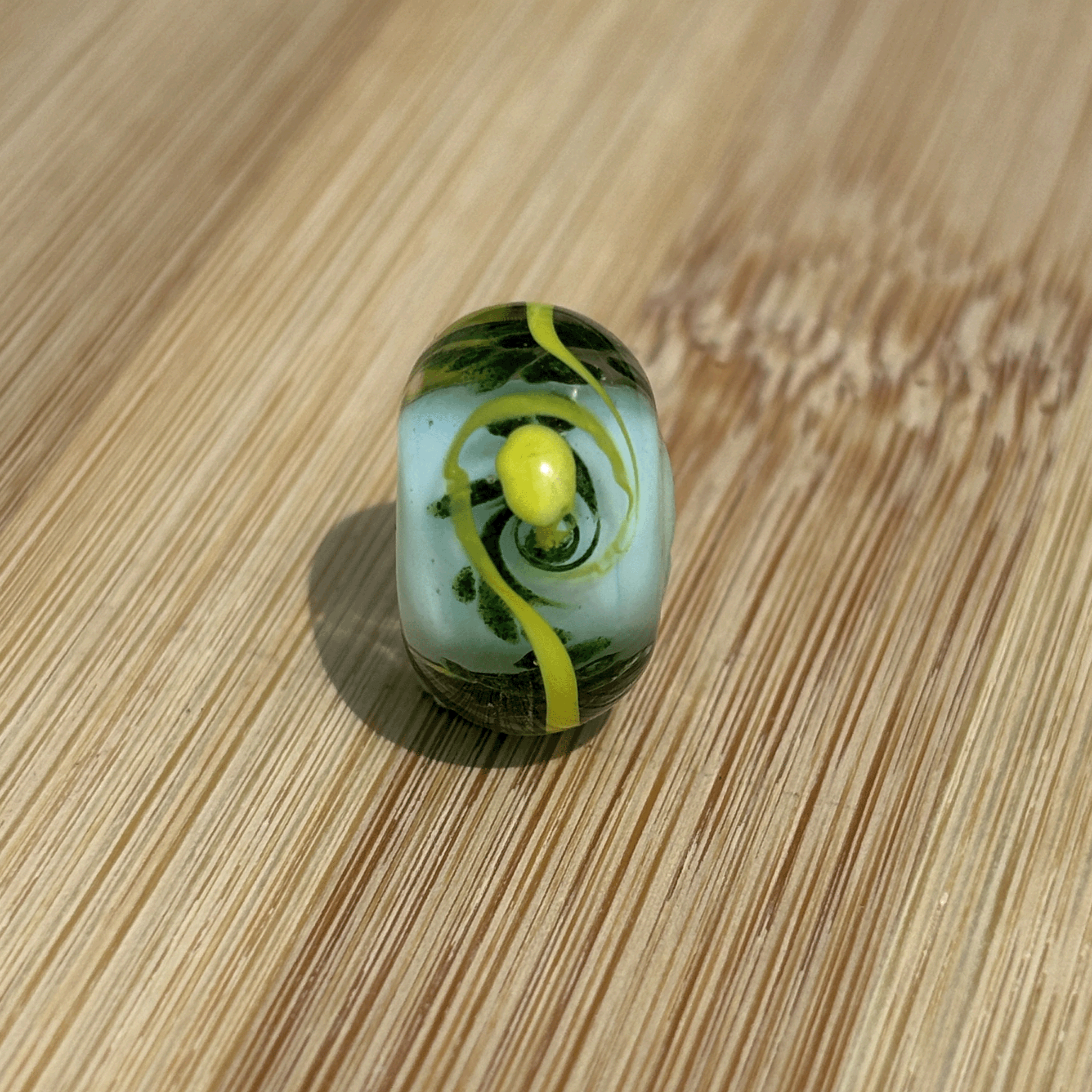 Blue, green and yellow glass bead being sold in support of EAND charity.