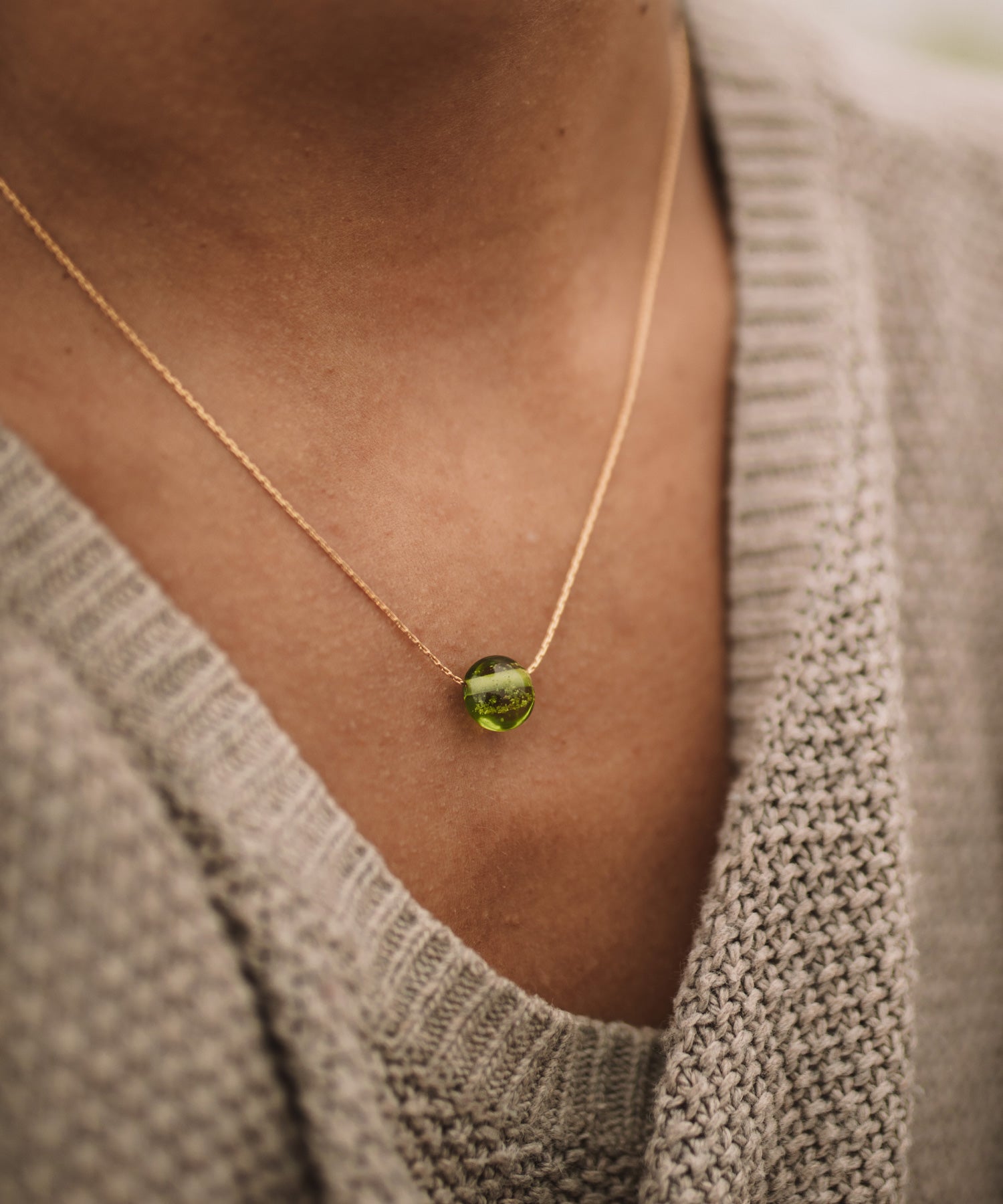 Green sand pebble on gold chain necklace.