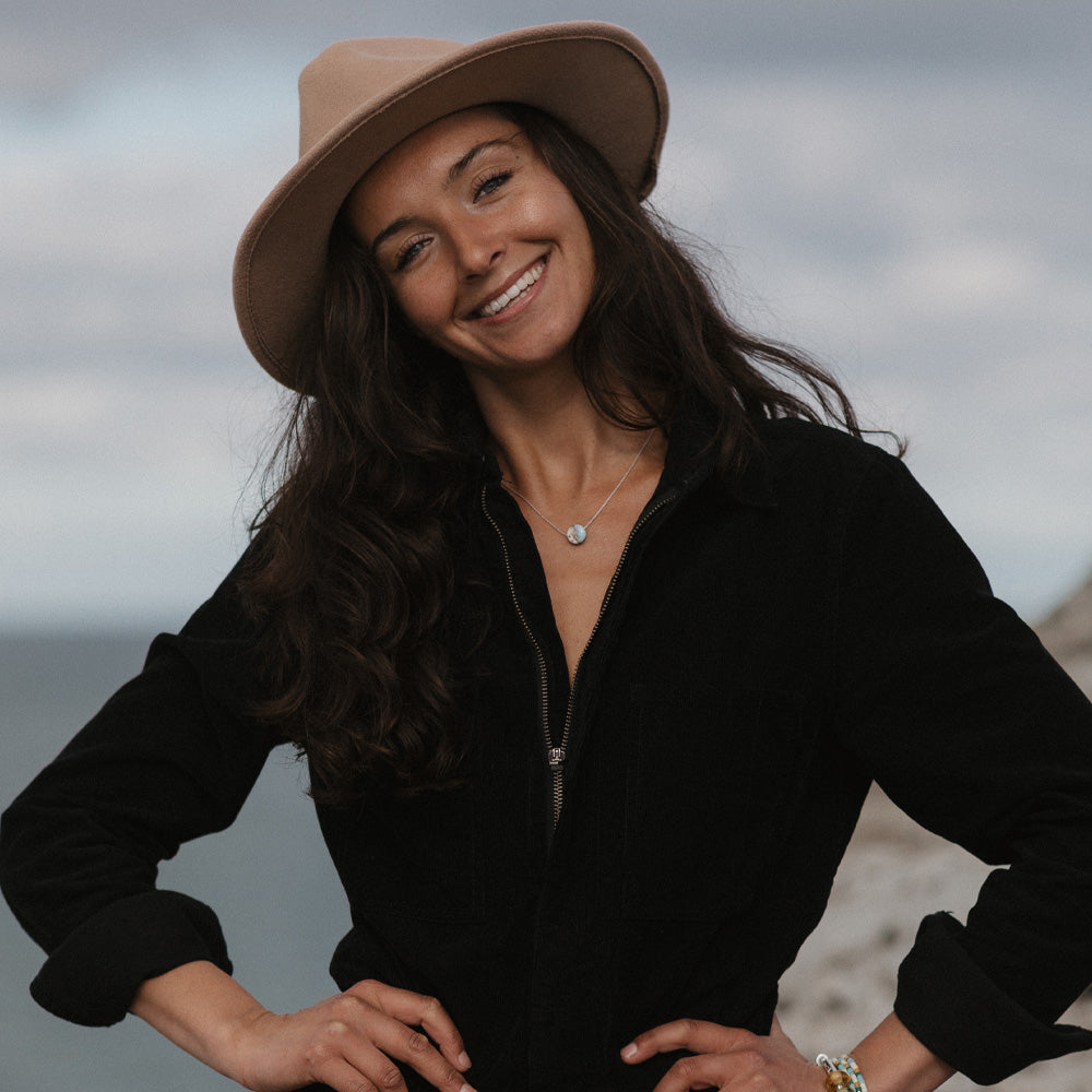 Woman wearing a beige hat and black outfit with a blurred background