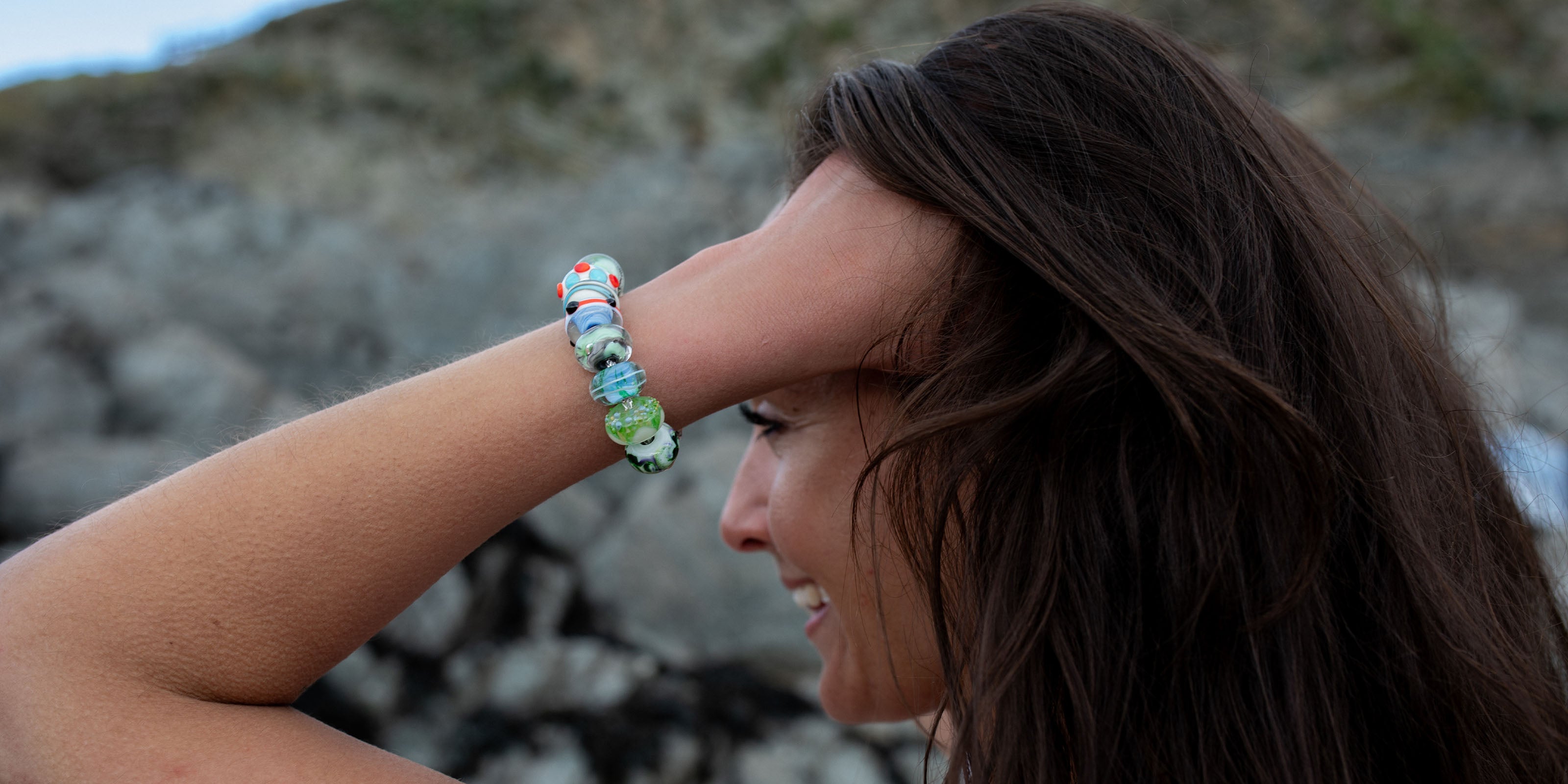 Woman wearing a bracelet with colourful glass beads representing Somersets beaches.