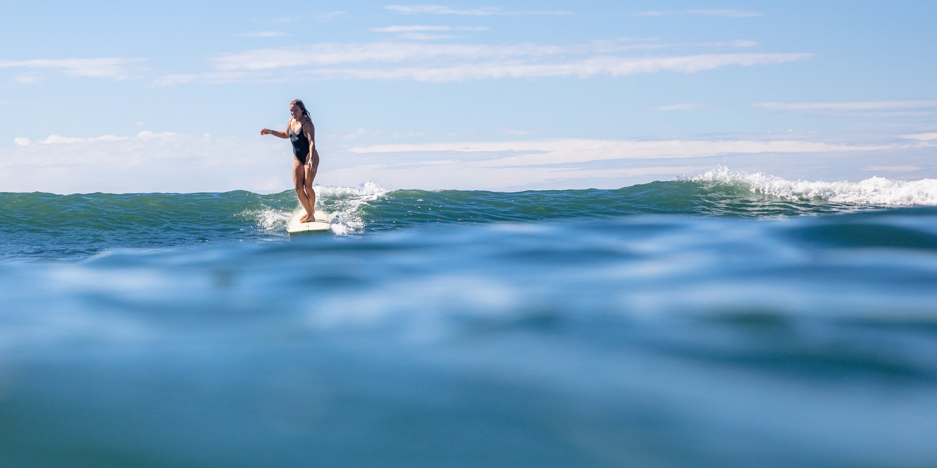 Girl surfing on her longboard surfboard in the sea in Australia.