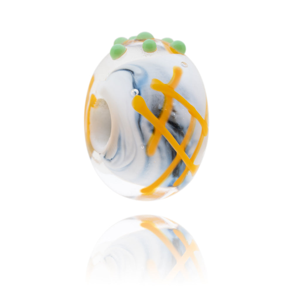 Black and white glass bead with a decoration of fish, chips and peas on the surface.