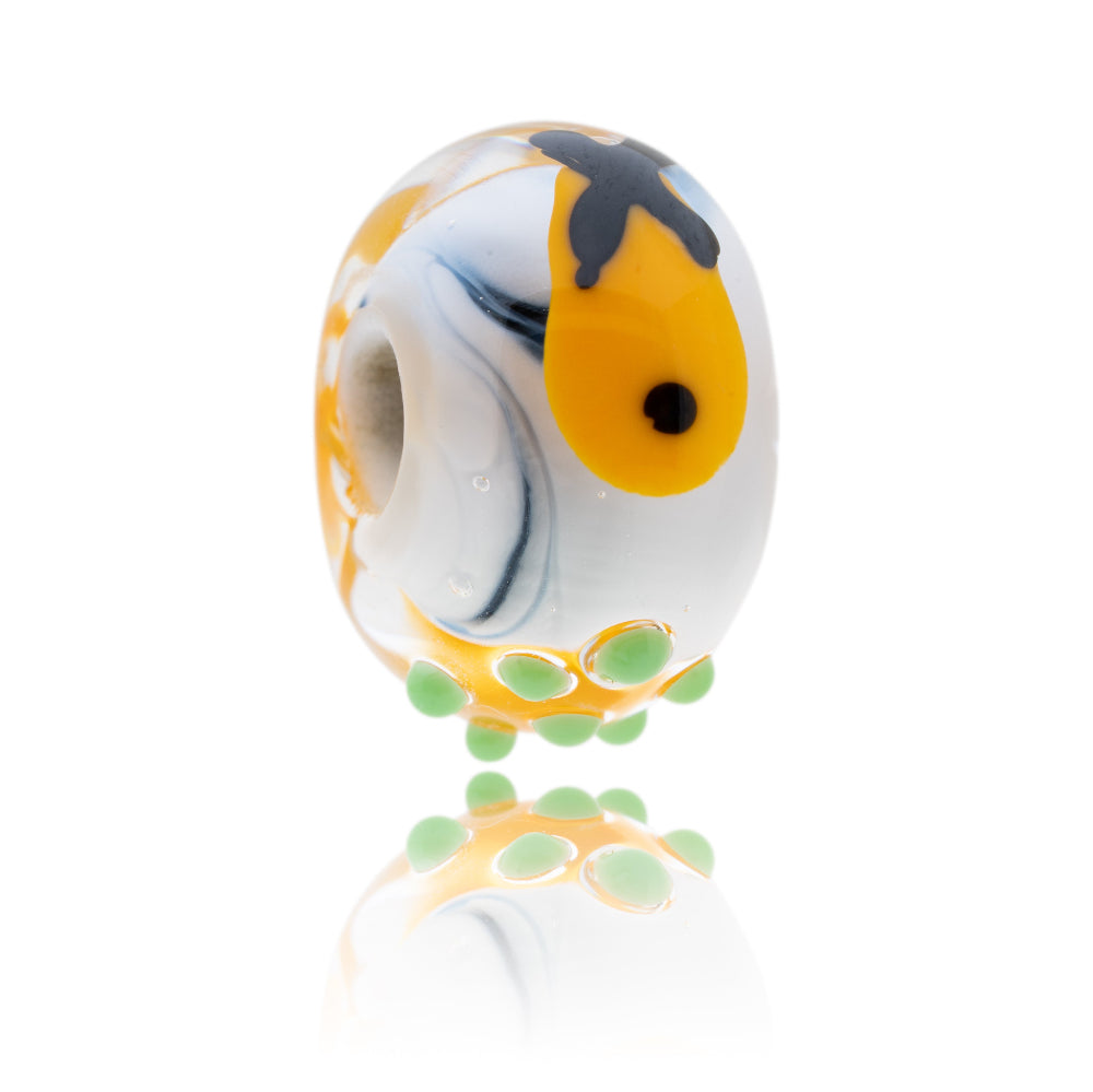 Black and white glass bead with a decoration of fish, chips and peas on the surface.