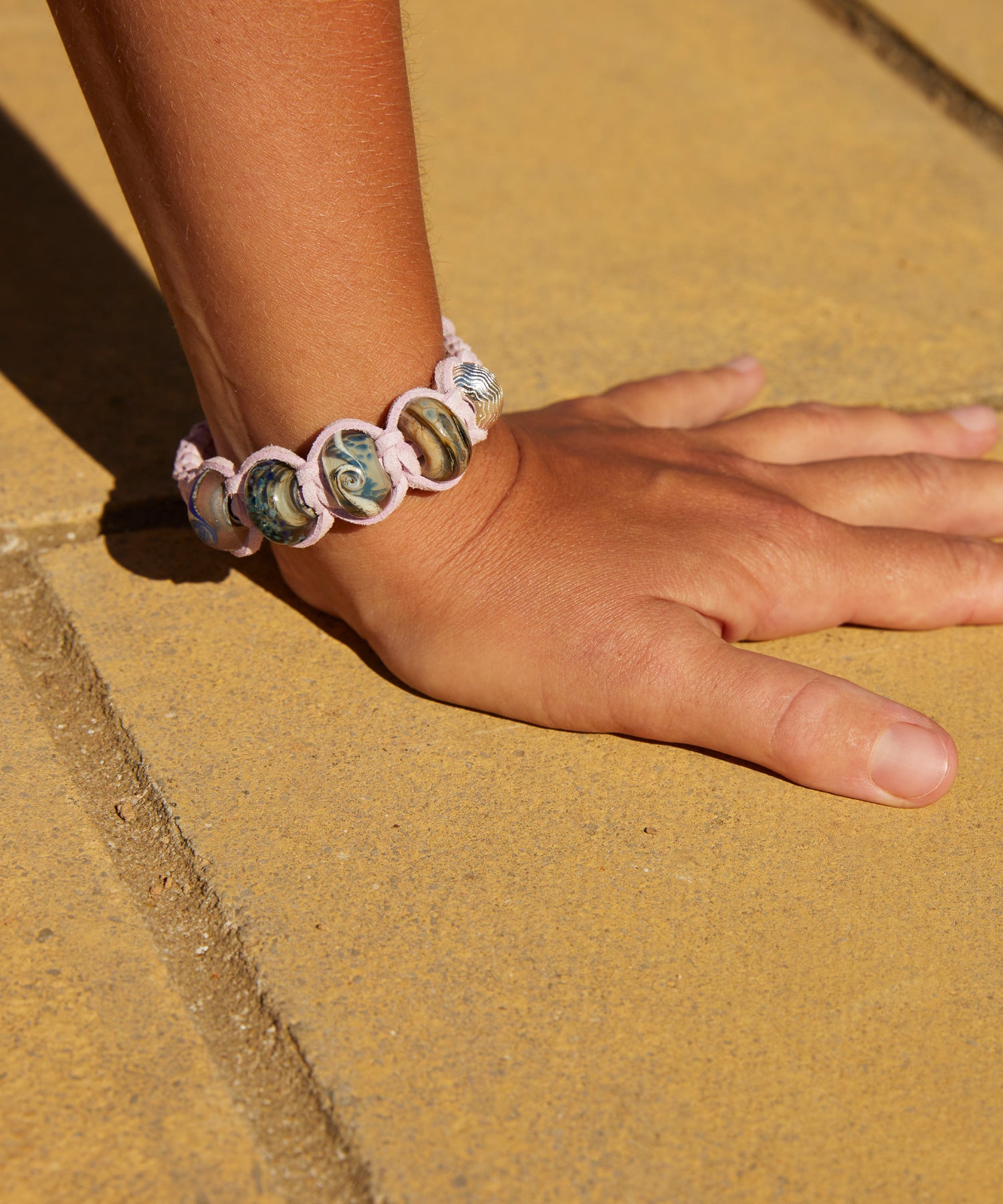 Thistle colour cord bracelet with blue and grey glass beads representing Northumberland beaches.