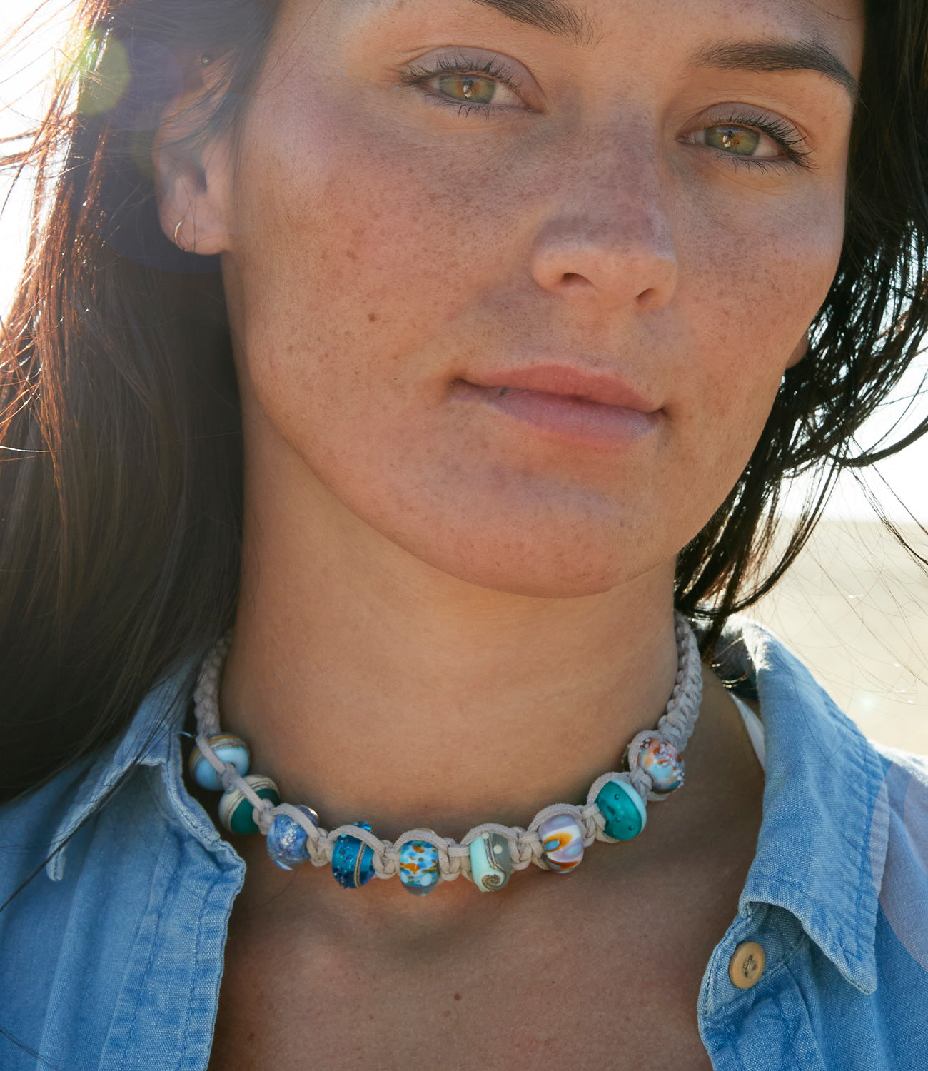 Colourful glass bead choker necklace worn by girl on the beach.