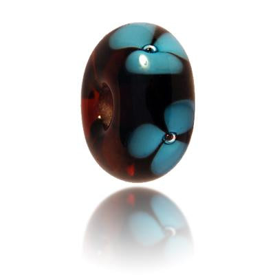 Brown glass bead with blue flower pattern on Surface for Fraserburgh in Scotland.