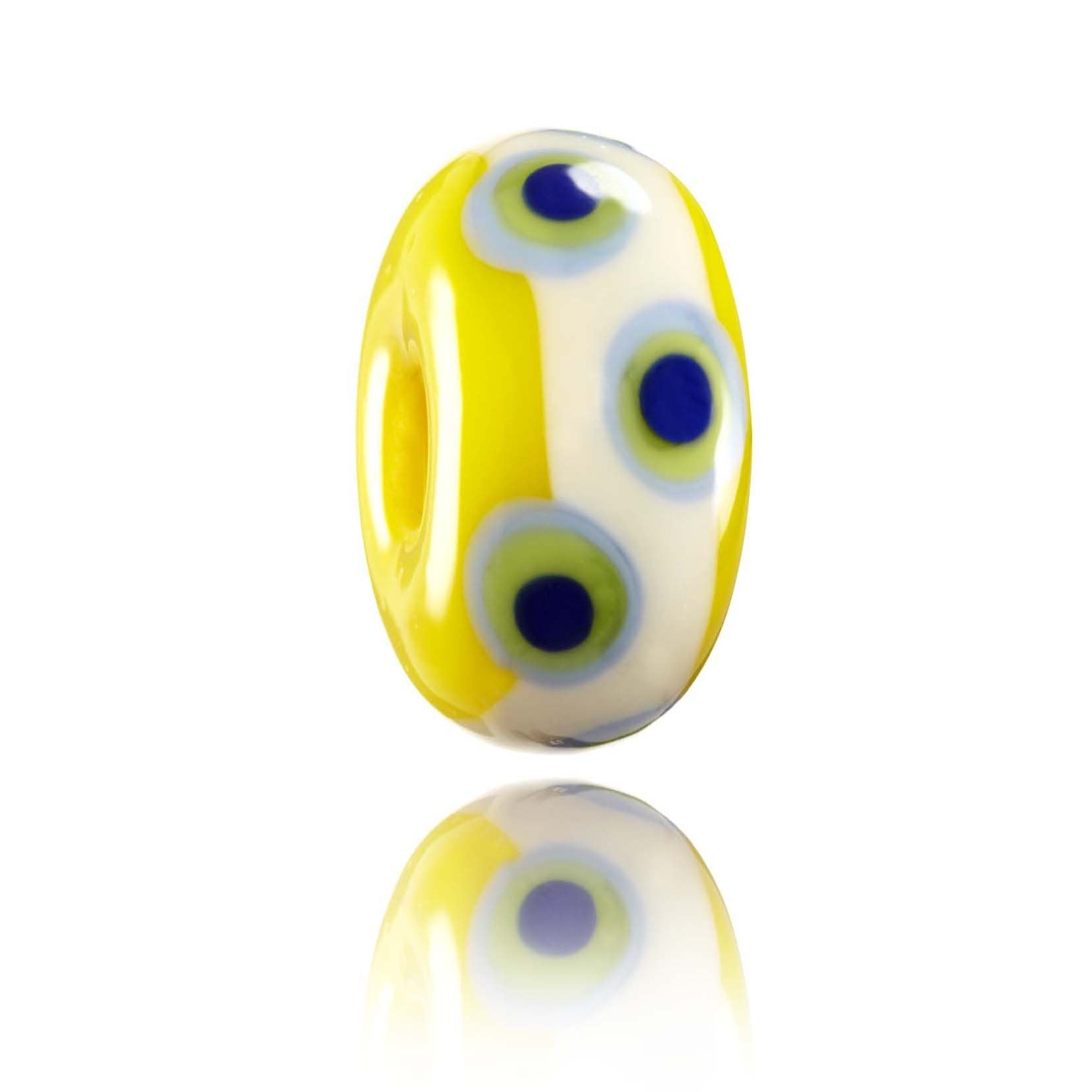 Yellow glass bead with cream and green and blue dot patterns.