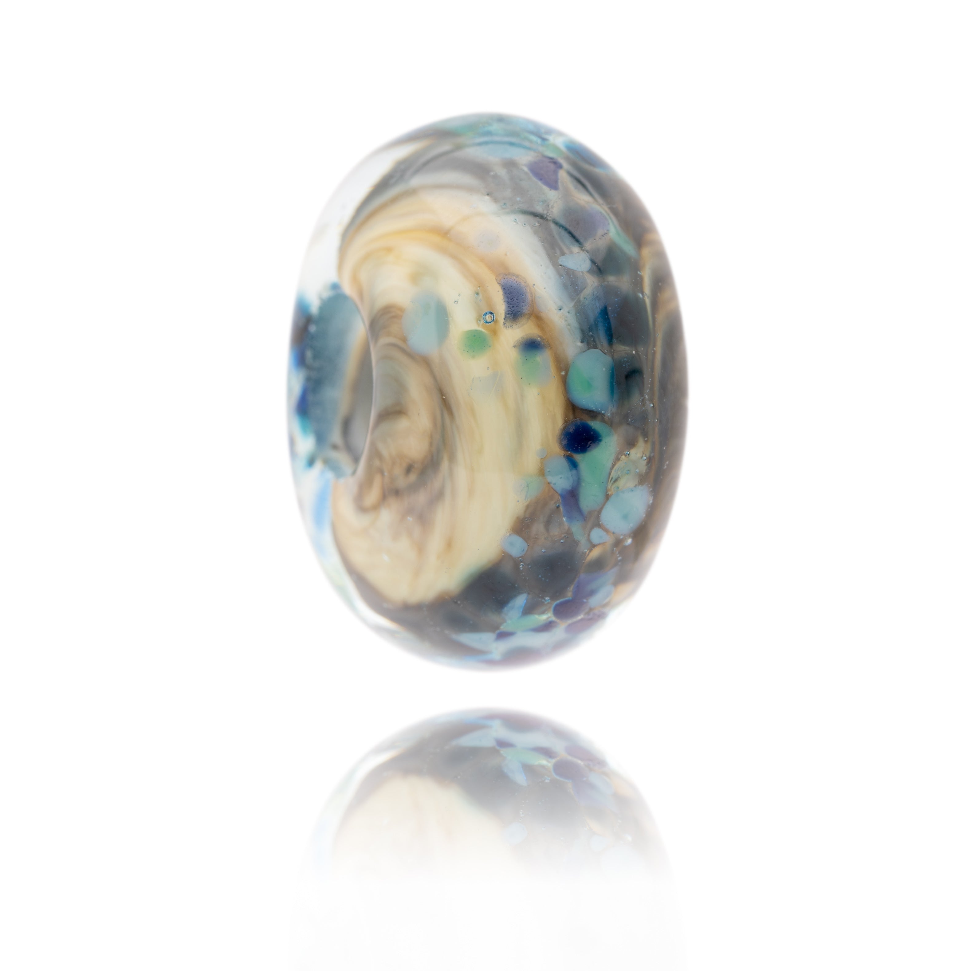 Born and cream swirling glass bead with blue spots on surface representing Cresswell Beach in Northumberland.