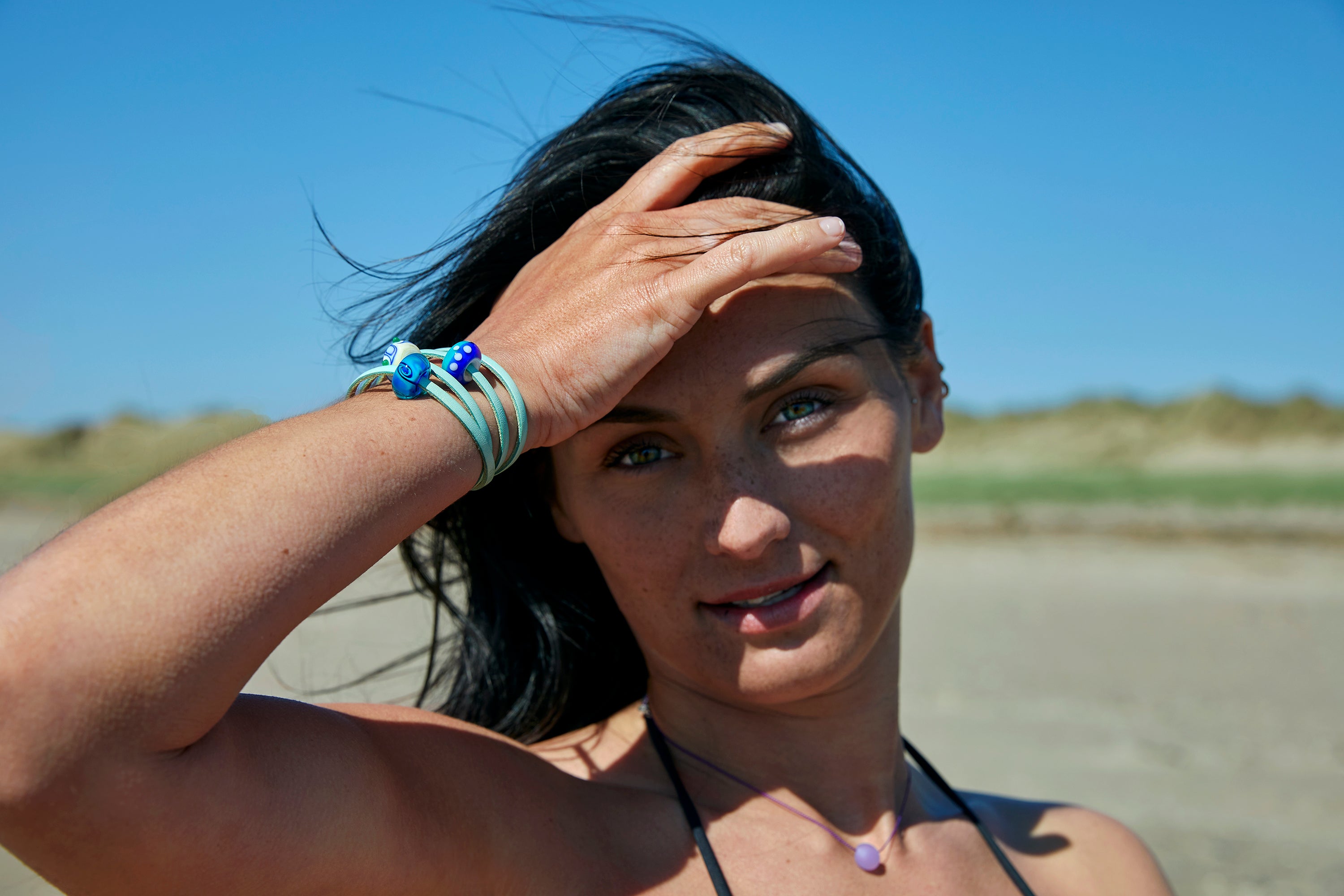 Blue swirling and patterned glass beads worn on turquoise leather wrap bracelet.