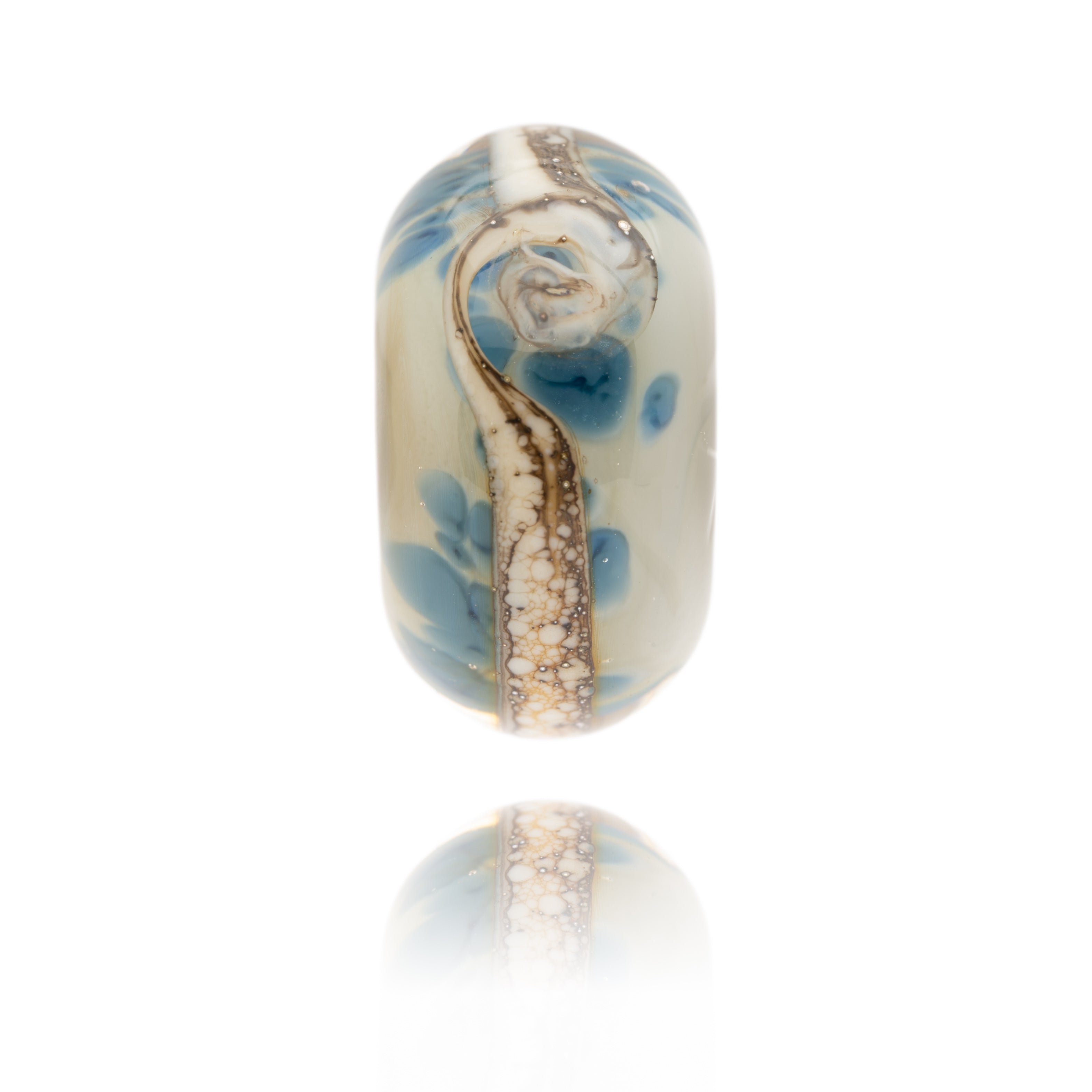 Cream glass bead with dark blue patterns within the glass. This bead represents Bamburgh Beach in Northumberland.